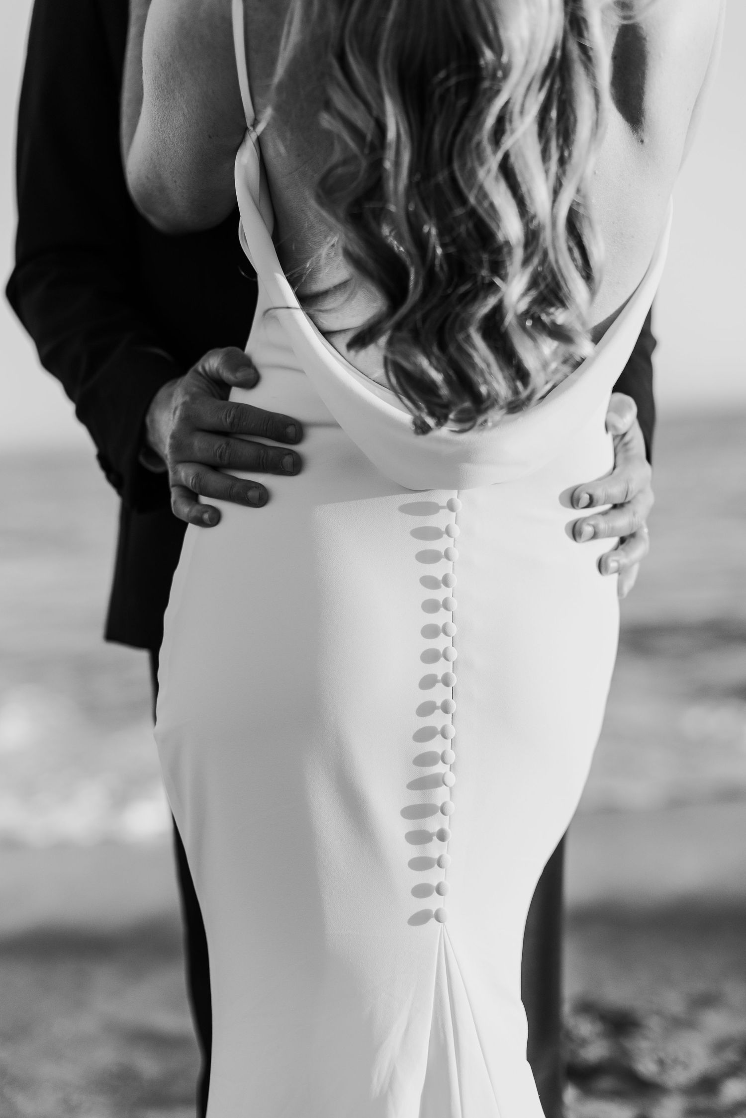Close-up details of a white wedding dress with elegant button closure down the back.
