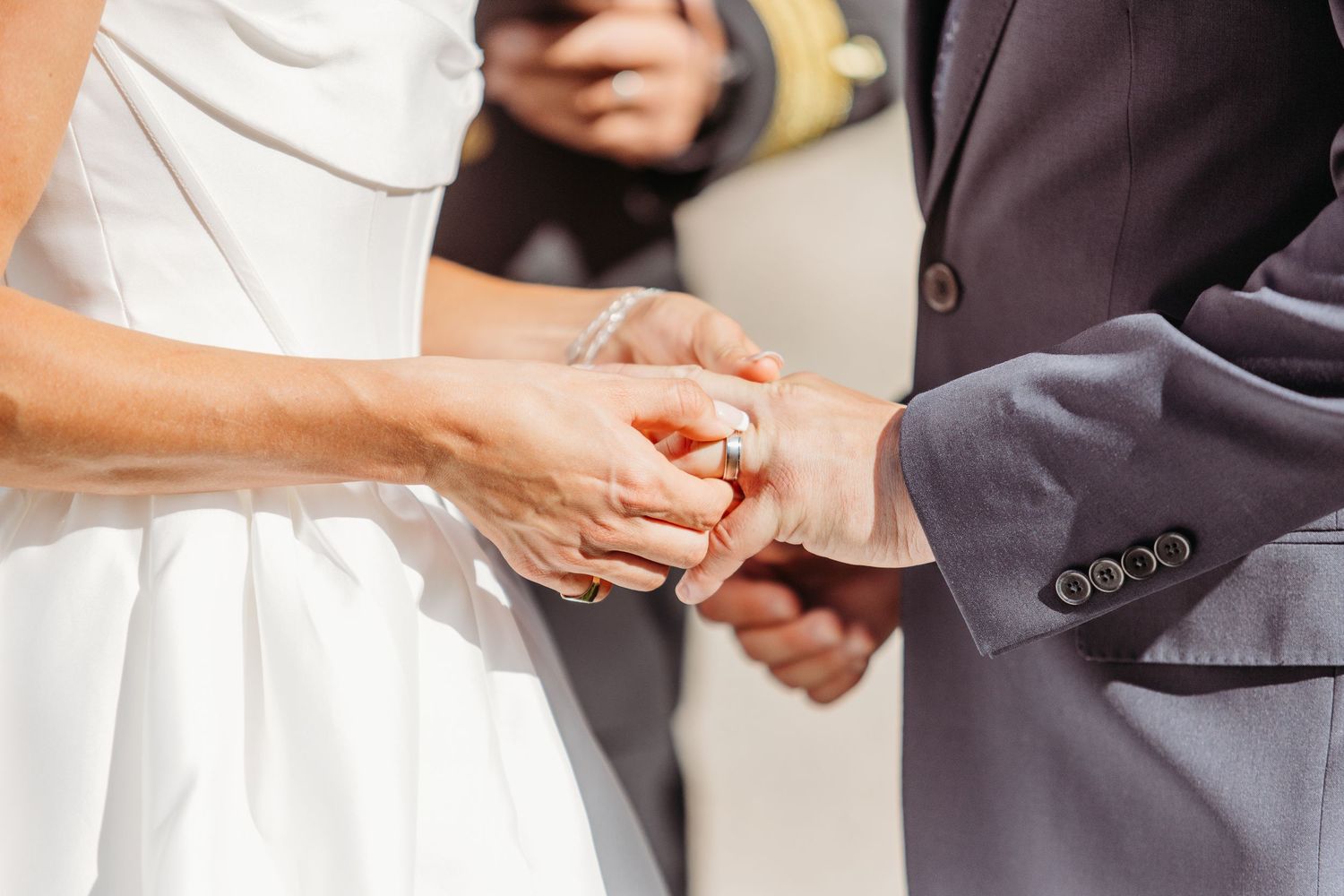 Close up of hands exchanging wedding rings during a marriage ceremony.