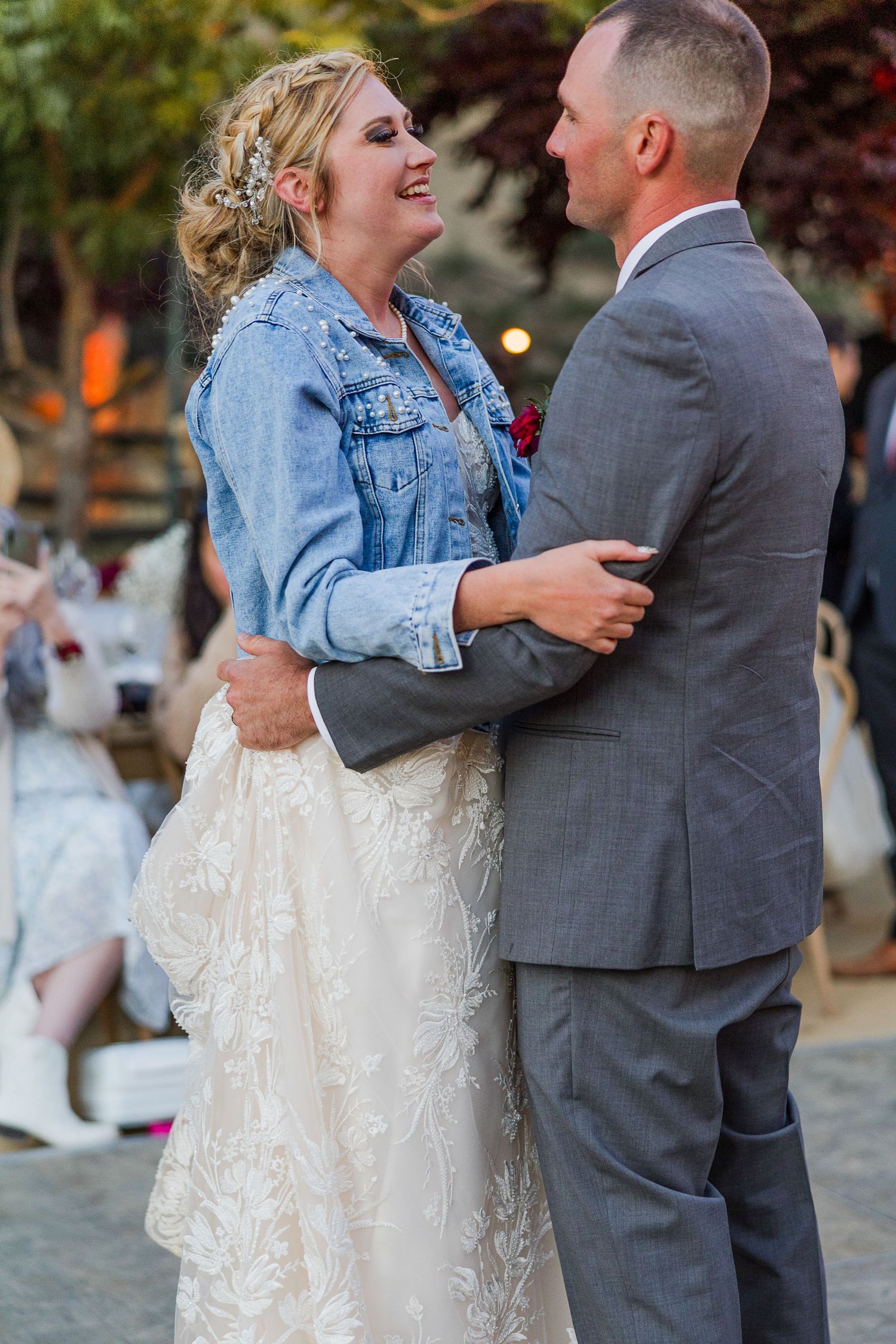 Happy couple shares intimate moment during wedding dance on outdoor patio.