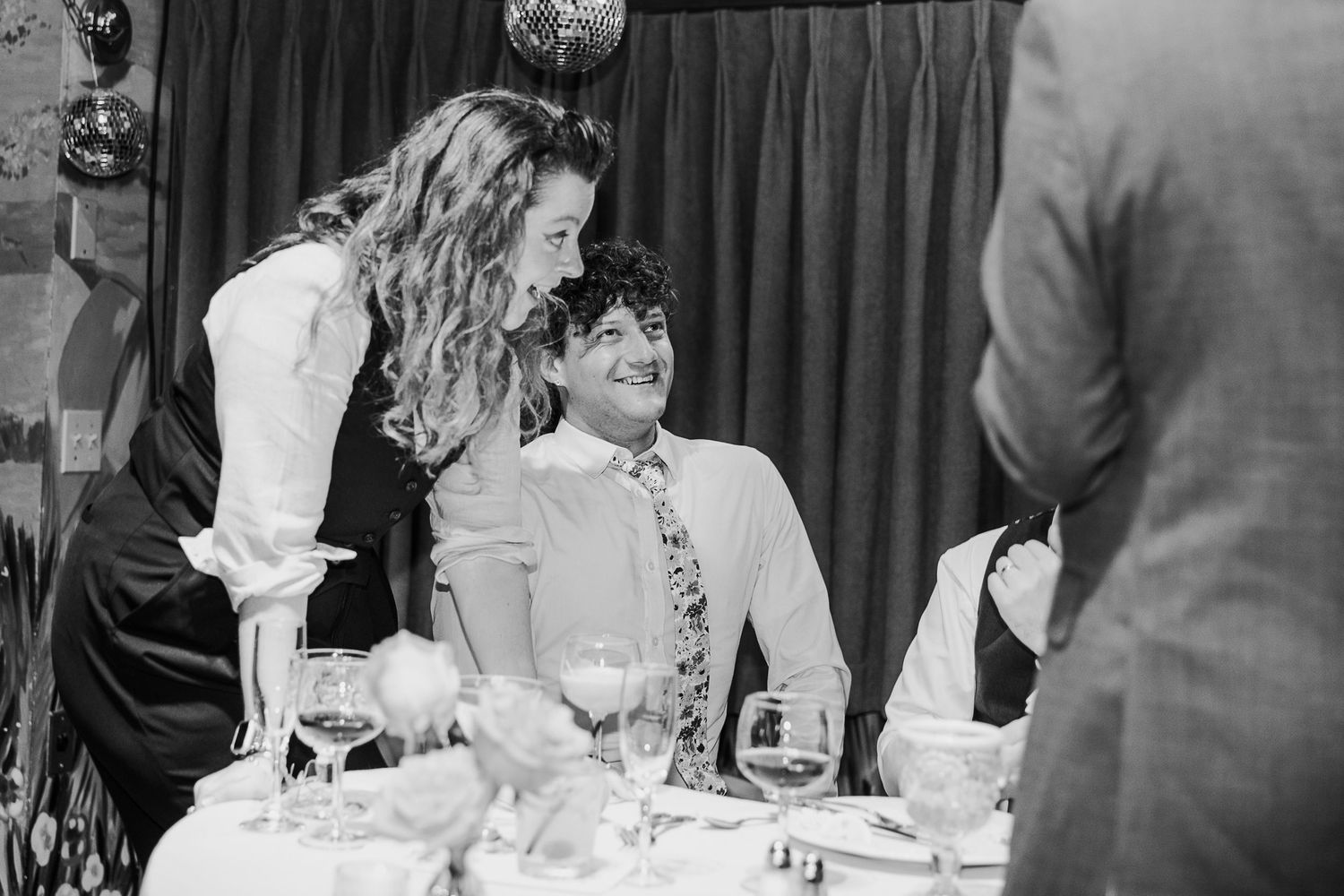 Black and white candid moments from wedding reception with dark curtain backdrop.