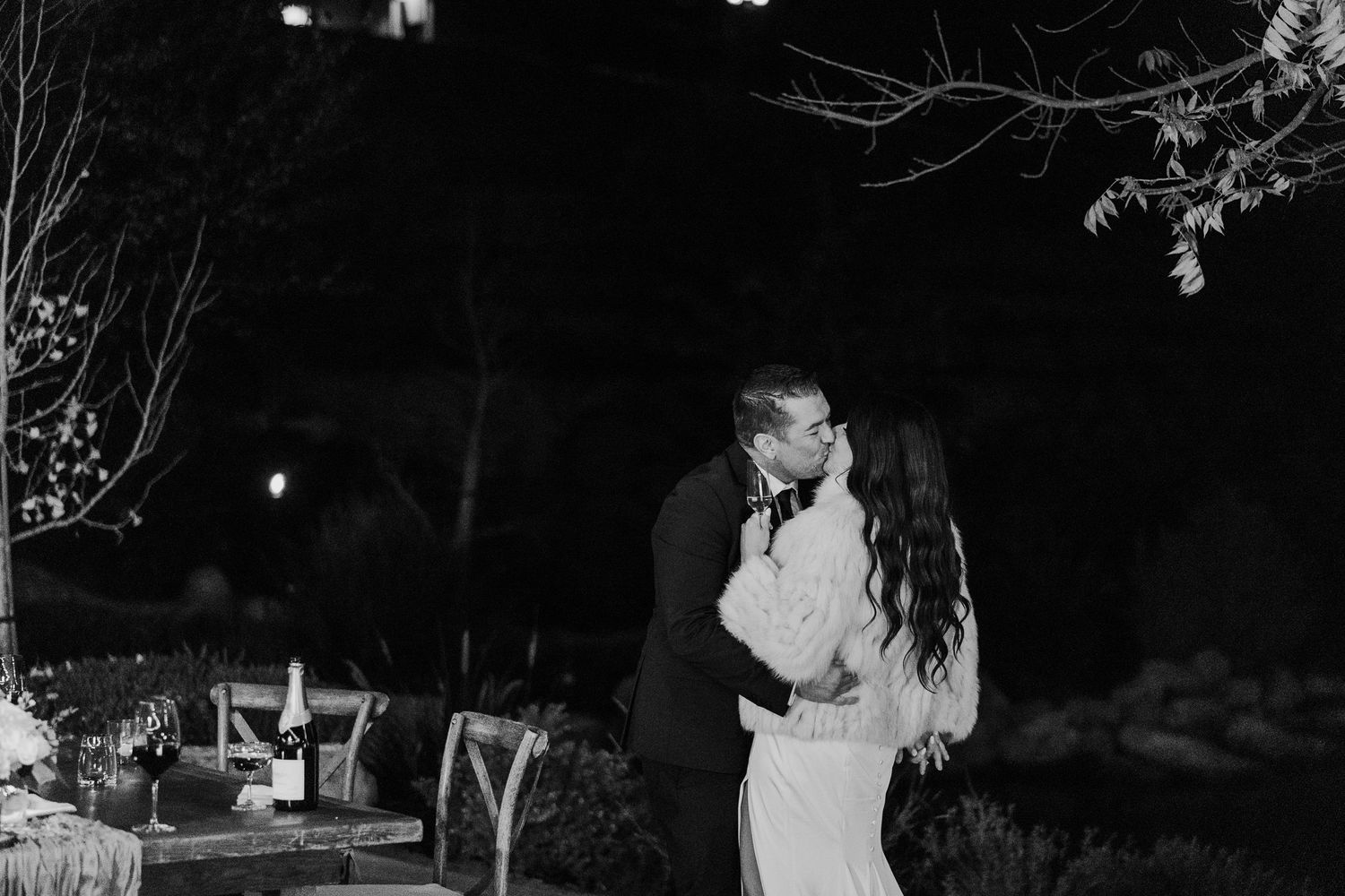 Outdoor nighttime wedding reception with string lights creating romantic ambiance.