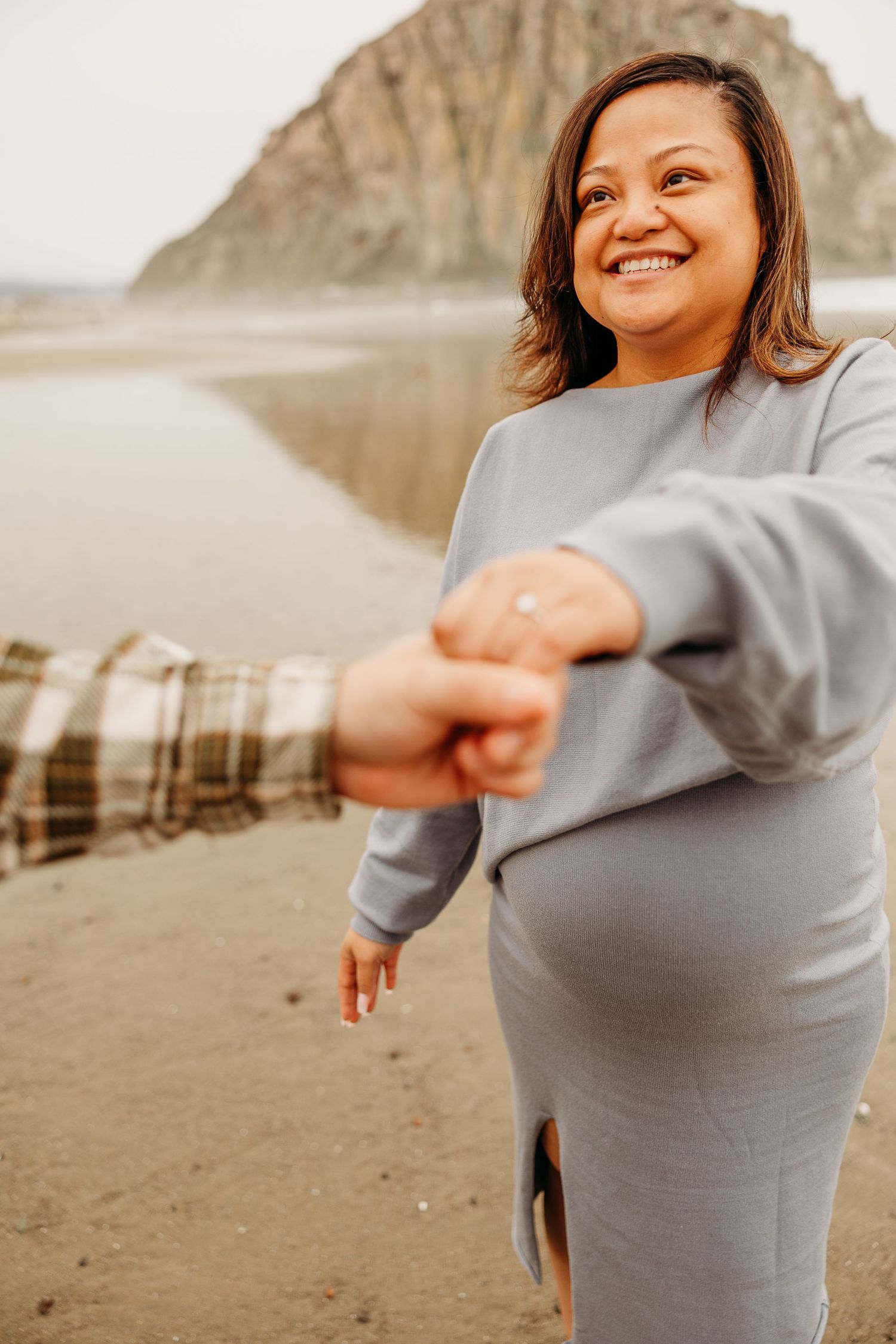A joyful moment captured on a beach with Morro Rock visible in the background.