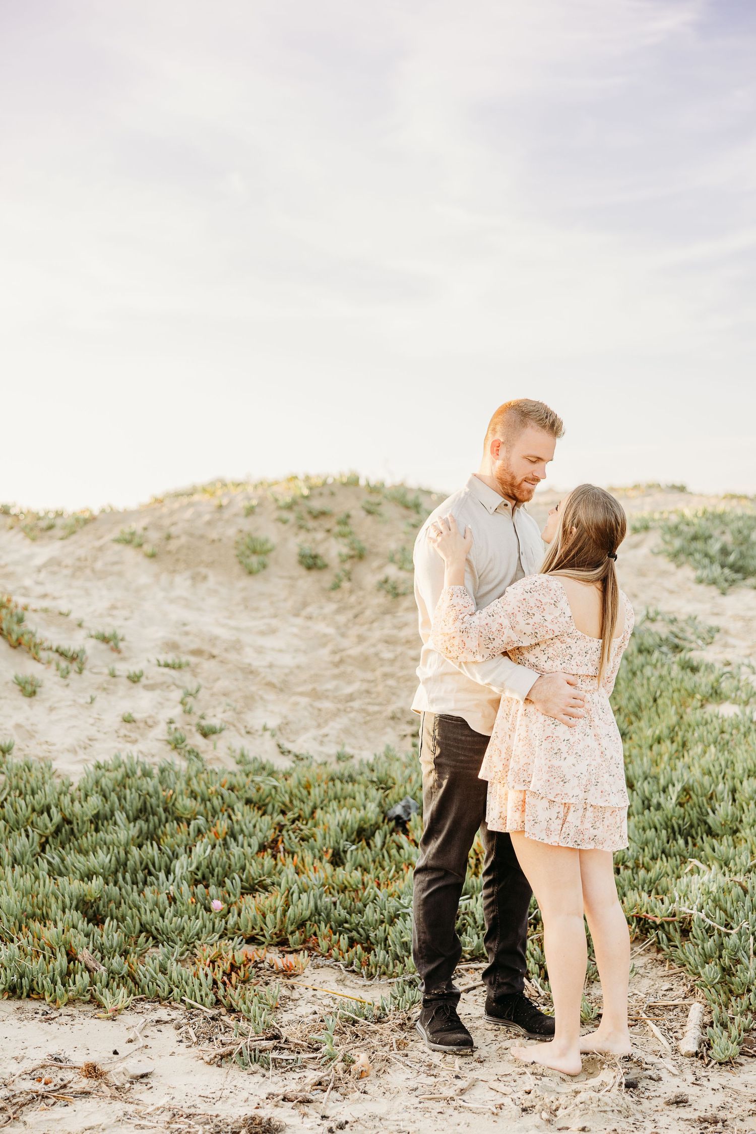 A tender embrace captured on a grassy hillside during golden hour.