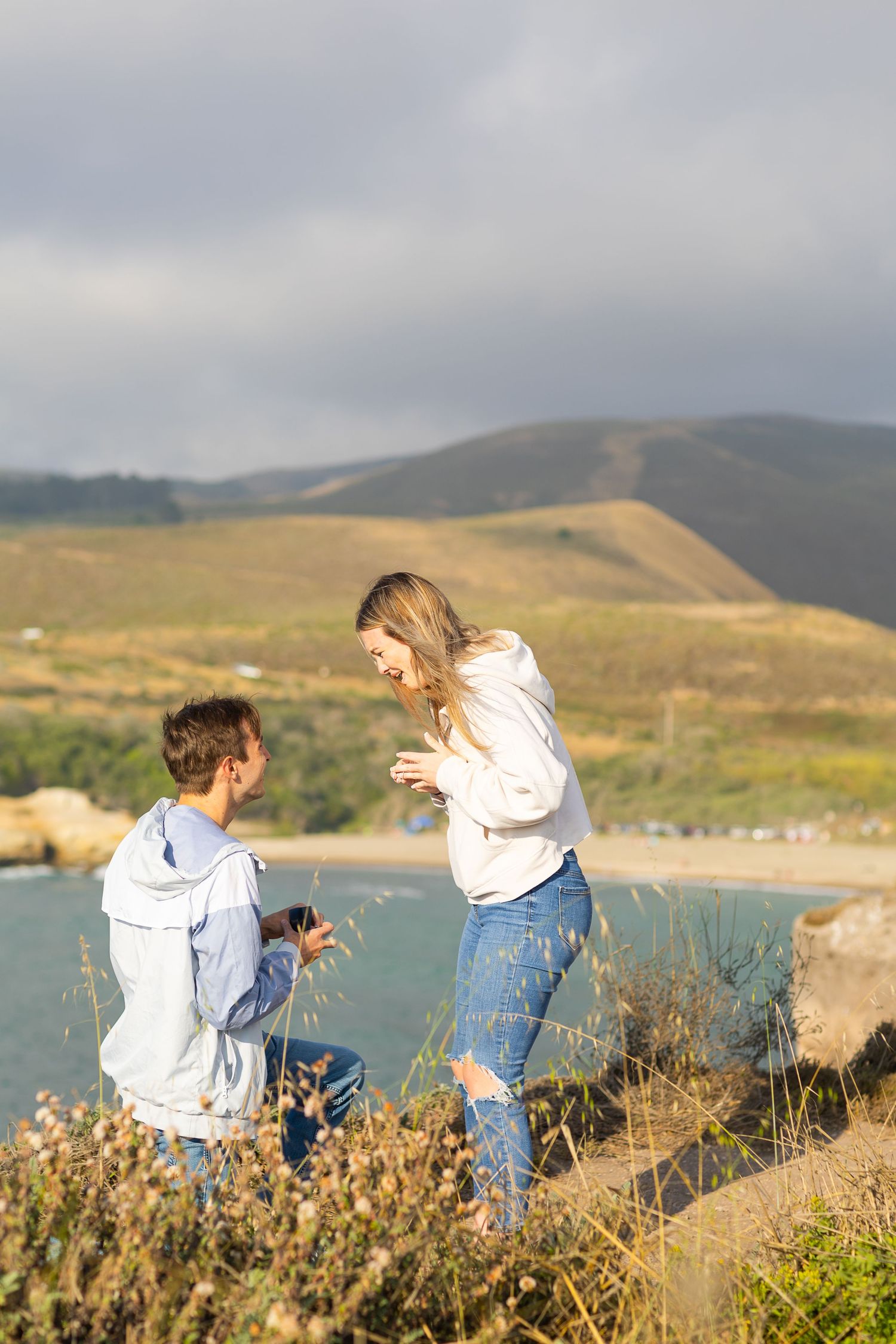A couple celebrating their engagement on a scenic coastal overlook.