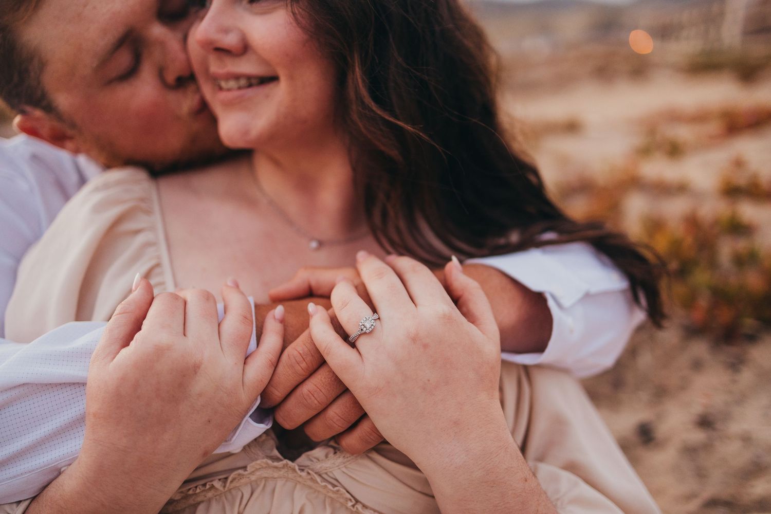 Close-up shot of hands embracing against soft desert lighting.