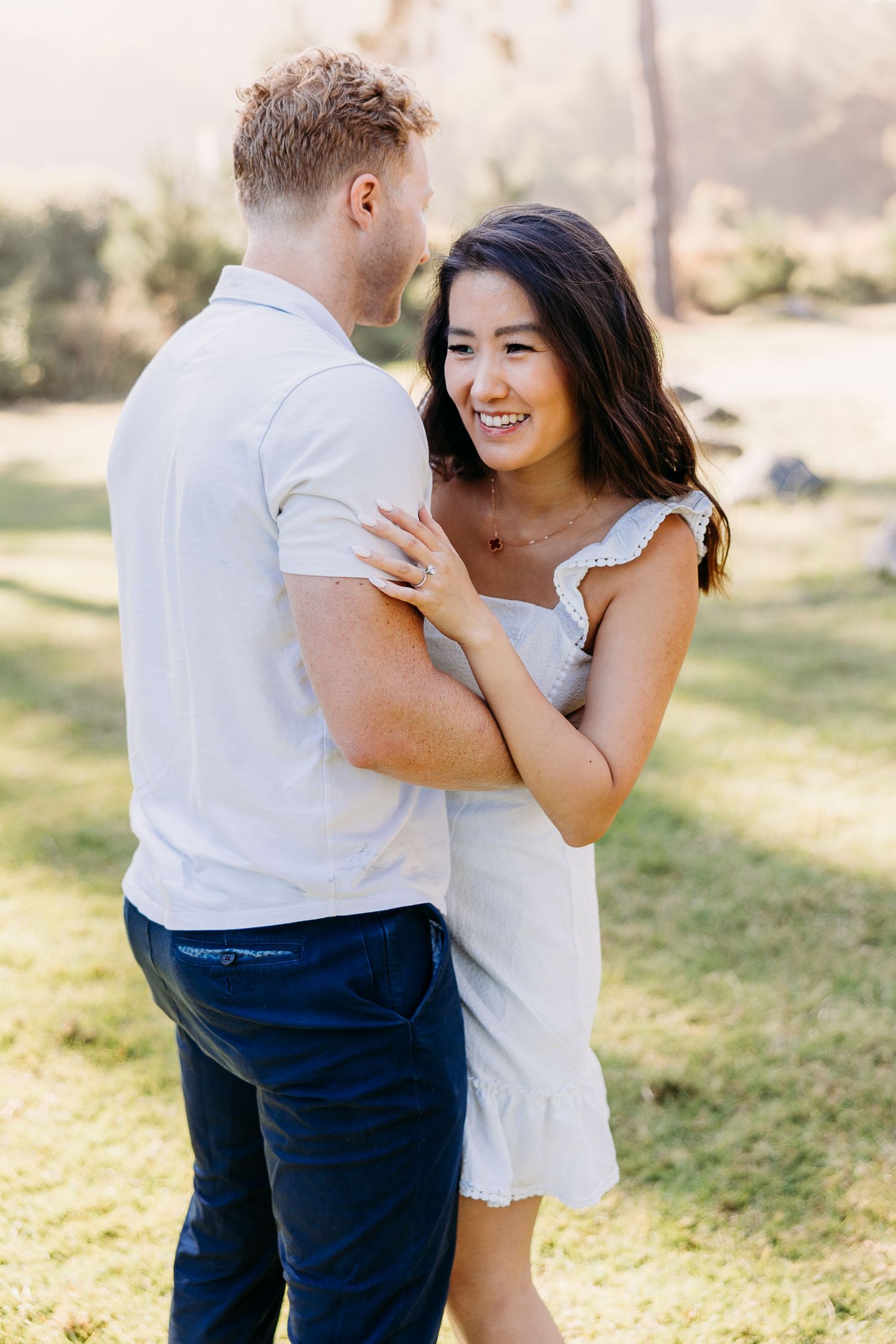 Couple in casual summer attire sharing a joyful moment in a park.