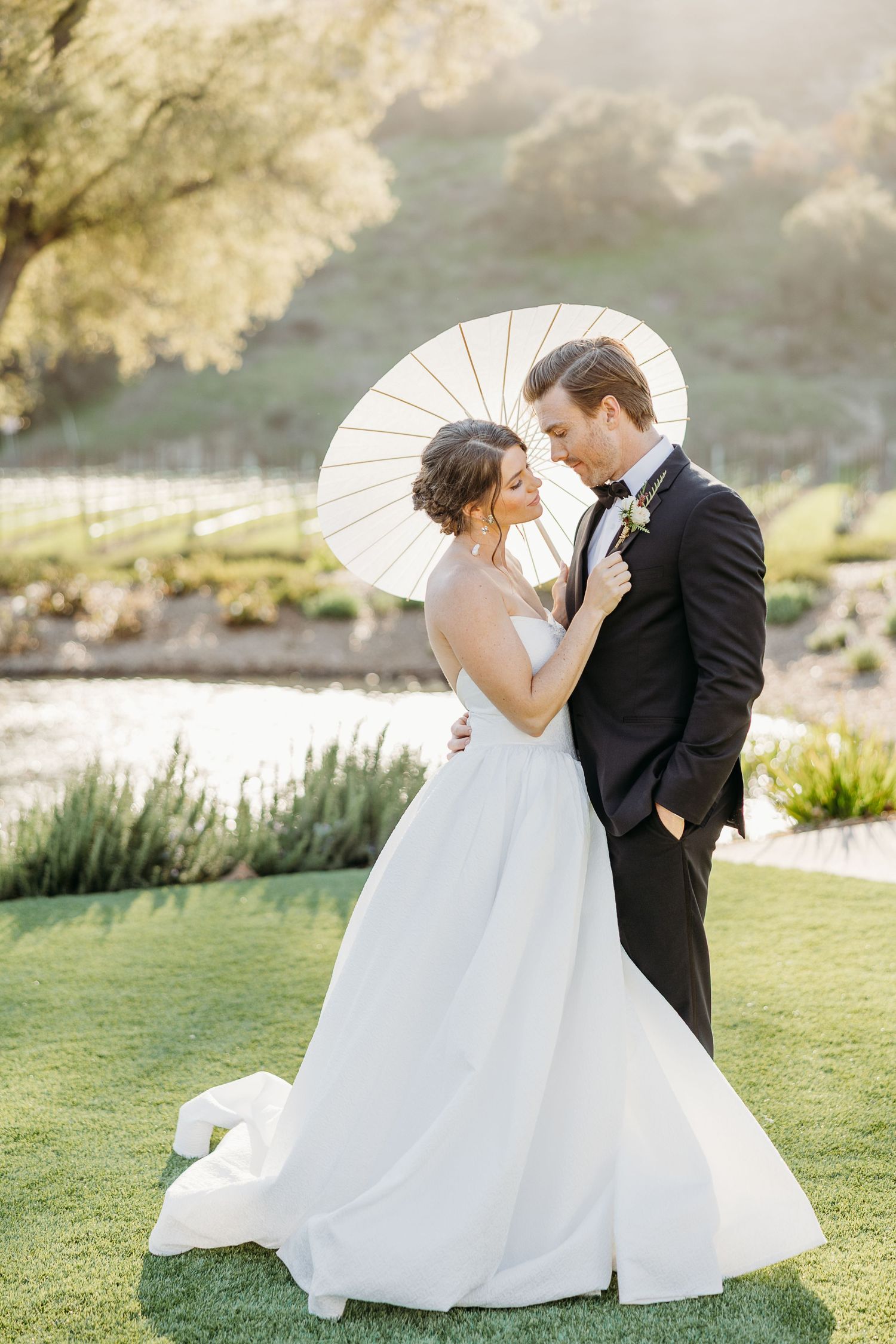A romantic wedding couple poses together in a garden setting during golden hour with beautiful natural lighting.
