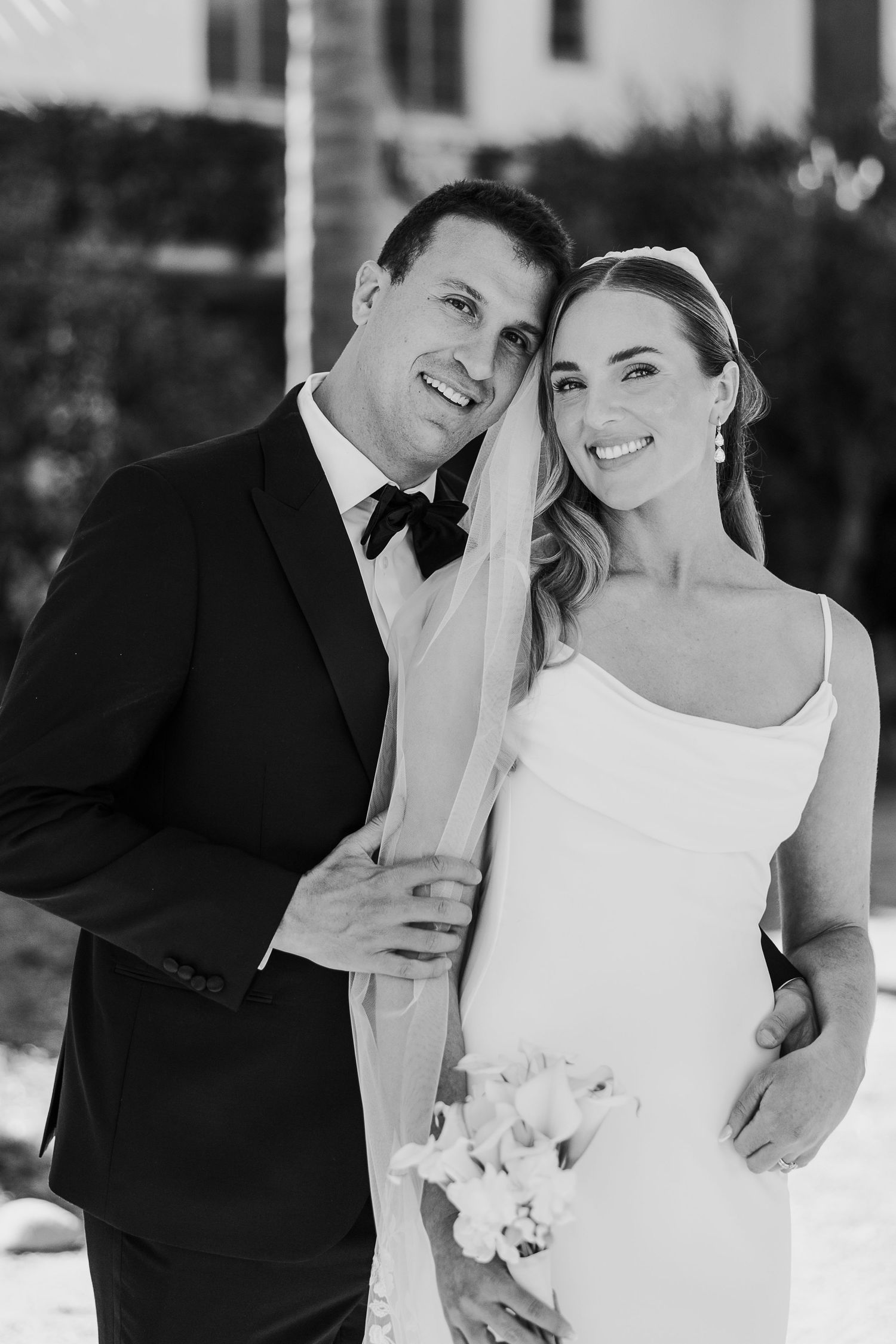 Black and white wedding portrait showing tender romantic moments between newlyweds outdoors.
