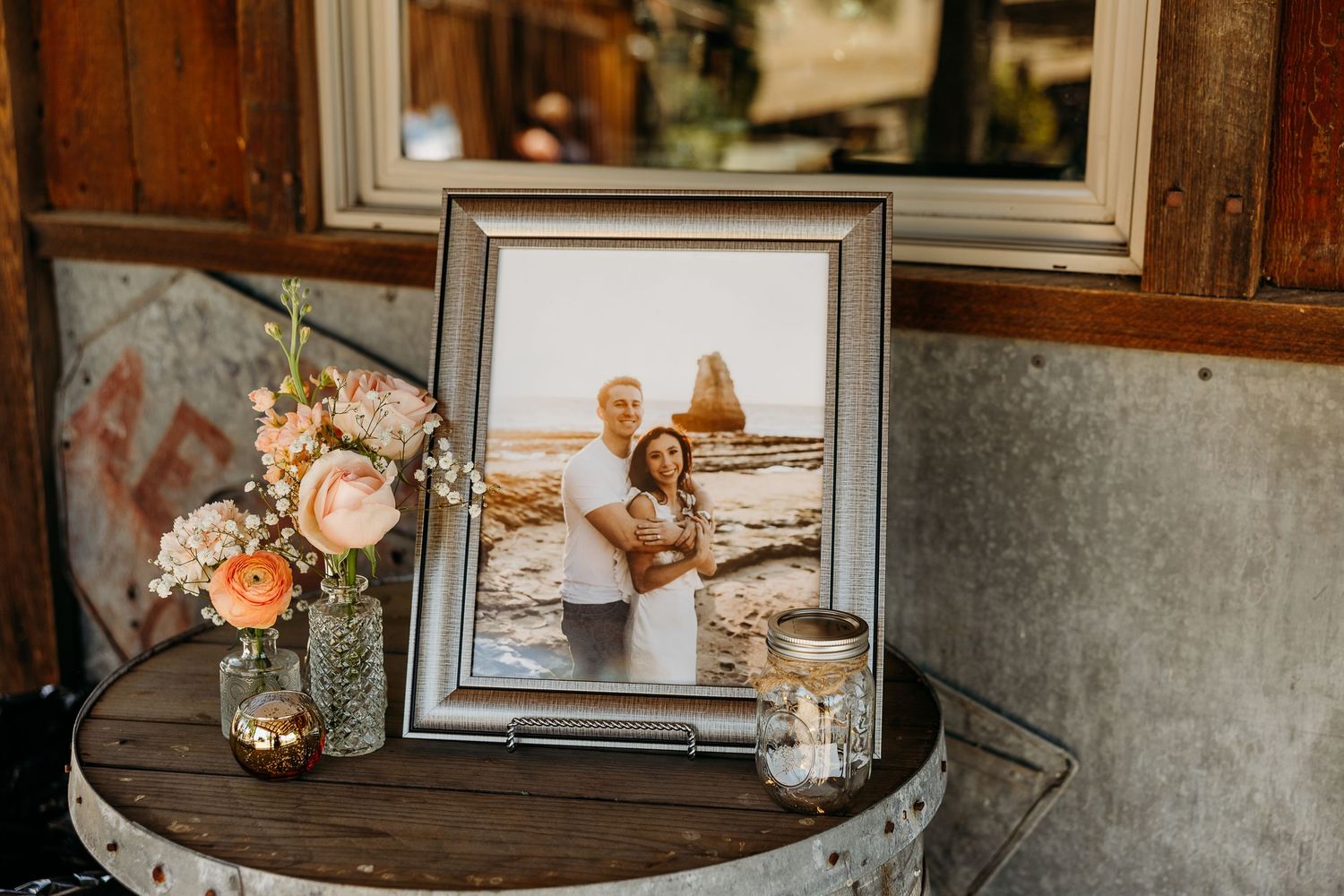 Rustic wedding reception venue decorated with vintage frames and floral arrangements.