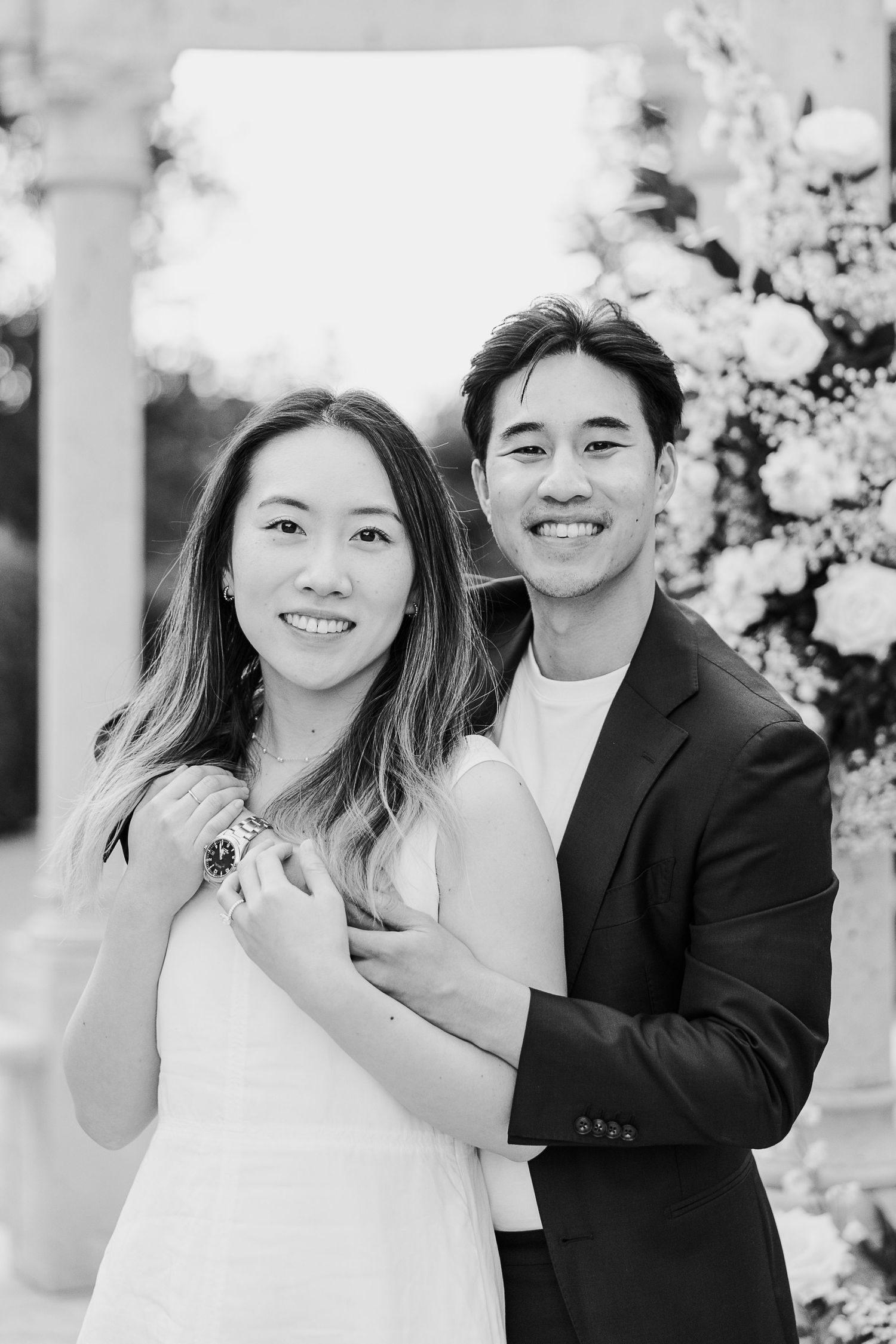 Joyful couple sharing a romantic moment among white floral decorations outdoors.