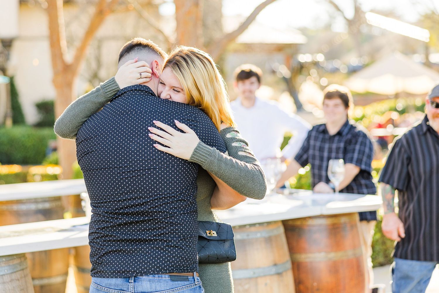 An emotional embrace captured during a surprise moment at an outdoor winery setting.