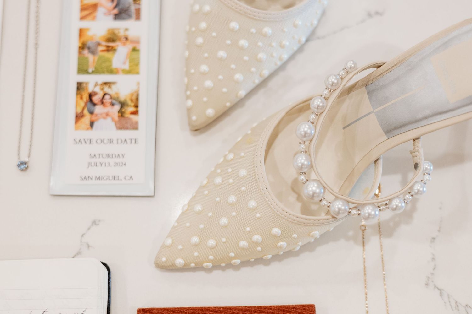 Elegant bridal shoe with pearl embellishments and wedding stationery details.