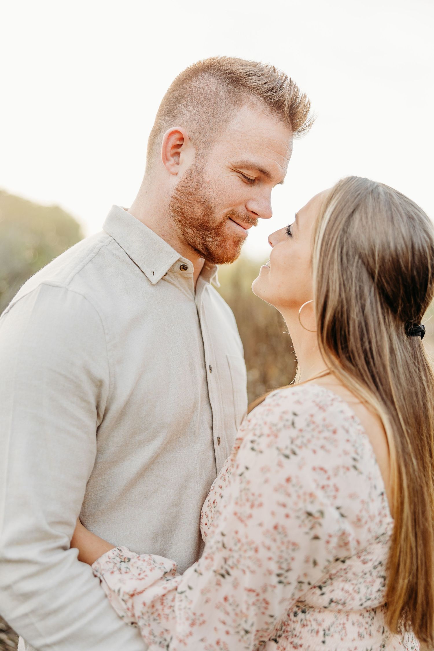 Intimate close-up of a couple gazing at each other against golden sunlight.