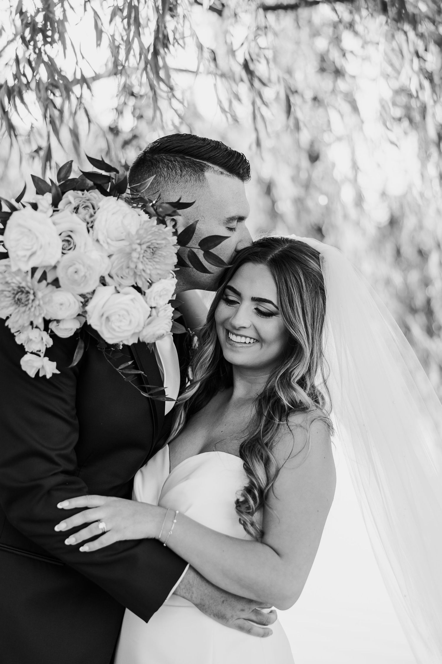 Black and white romantic wedding portraits showing tender moments between newlyweds with white floral bouquet.