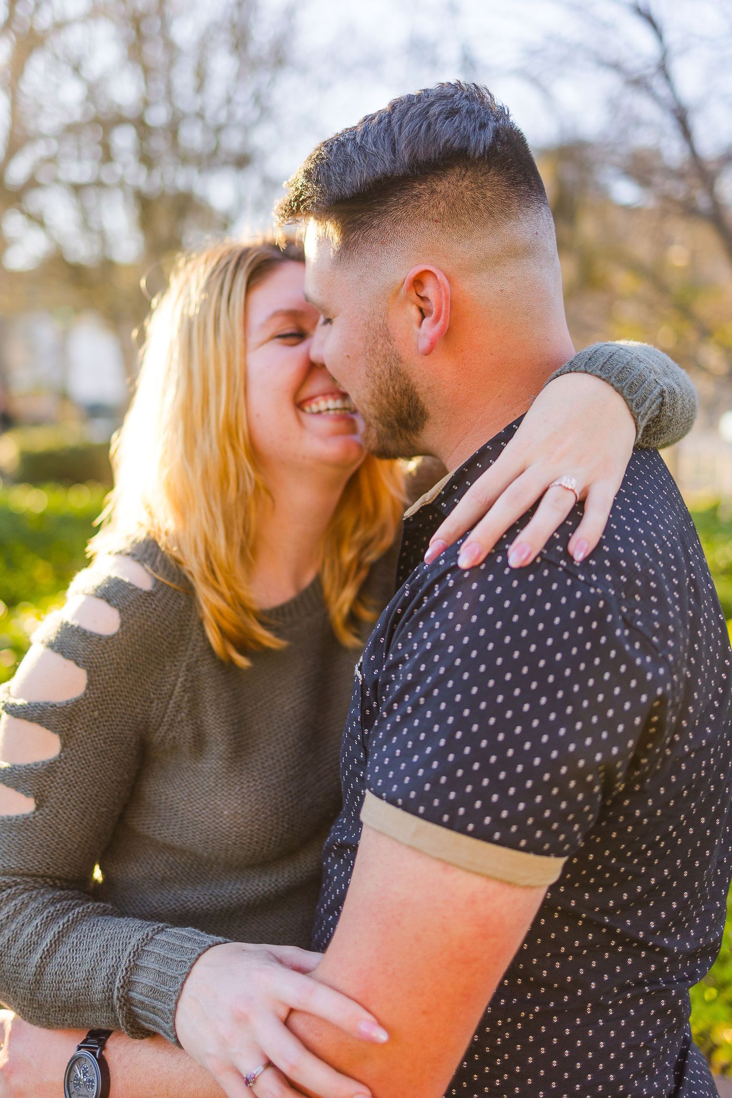 A sweet moment between a couple sharing laughter in a sunny garden setting.