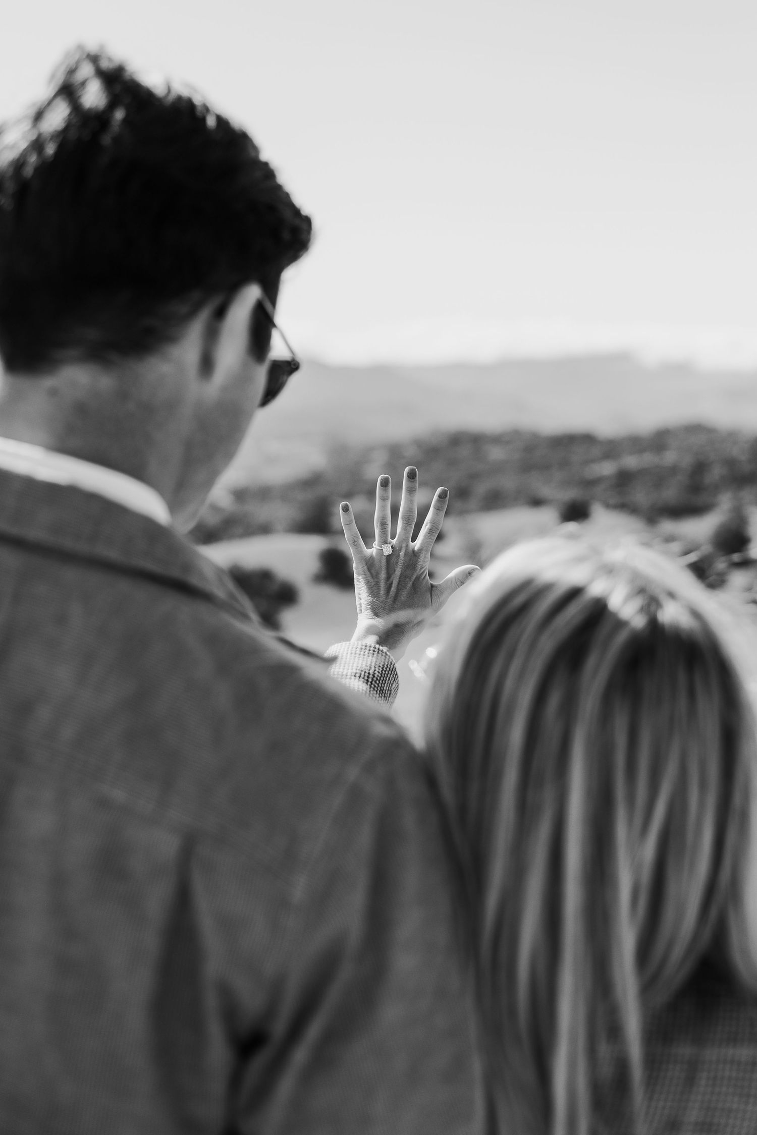 A black and white close-up shot of two people sharing an intimate moment outdoors.