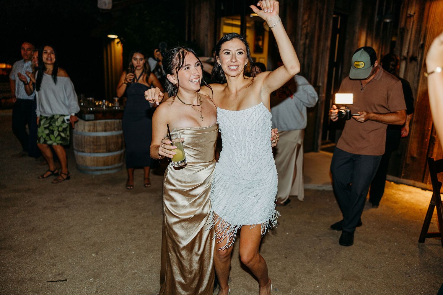 Wedding reception dance party with guests in formal attire at rustic venue.