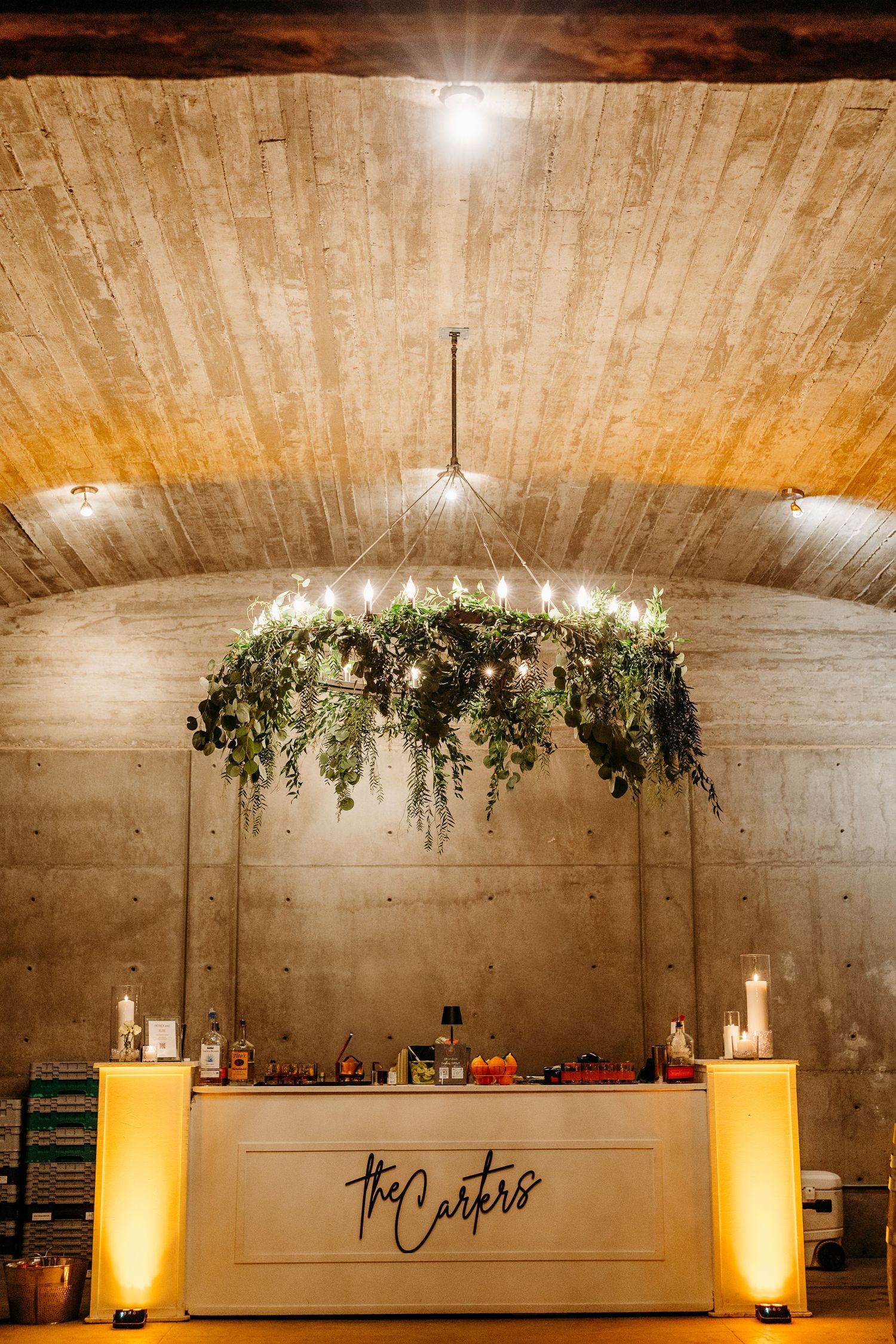 Modern reception space with hanging greenery installations and ambient lighting under concrete ceiling.