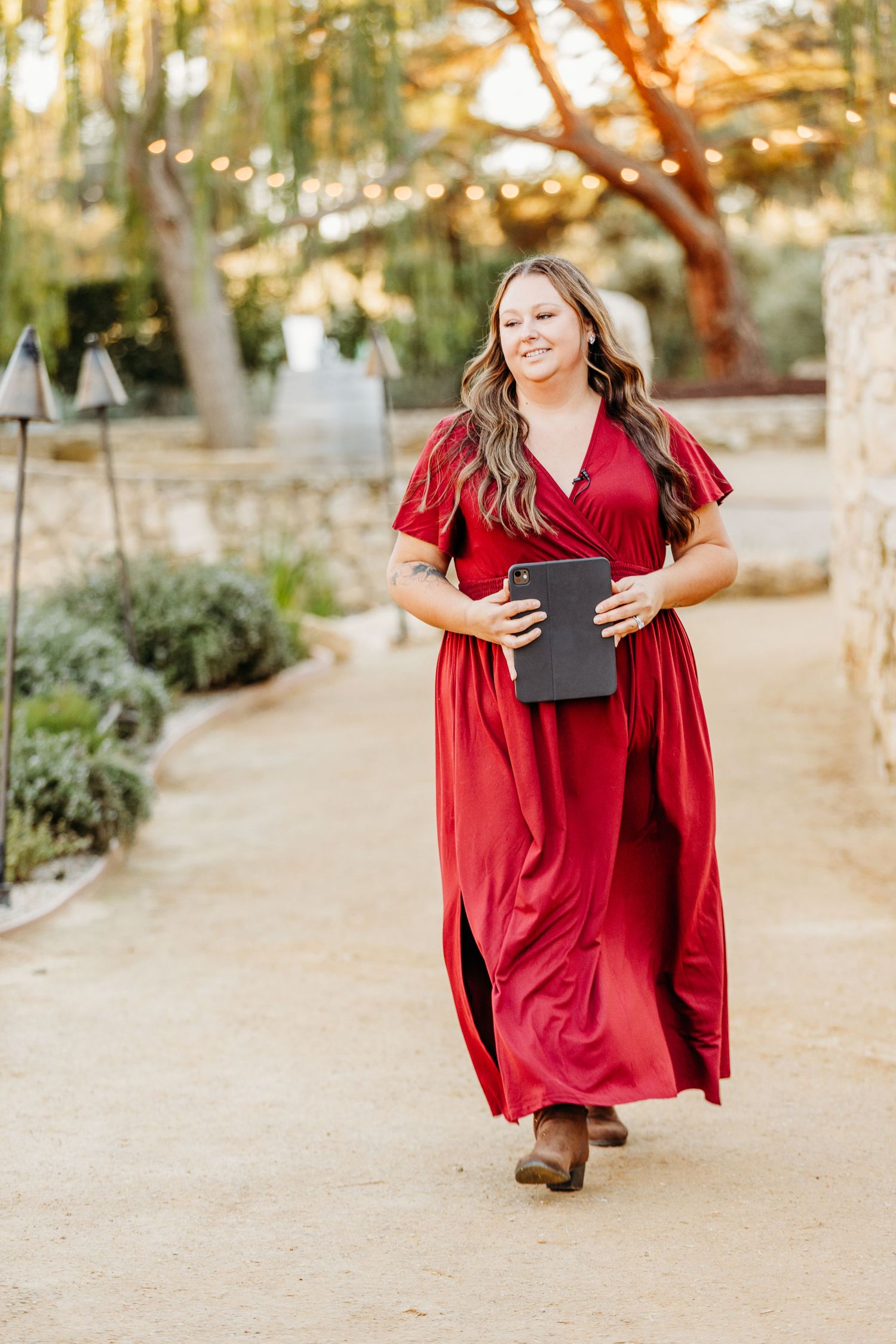 Women in flowing red dresses walking along a desert garden path at sunset.