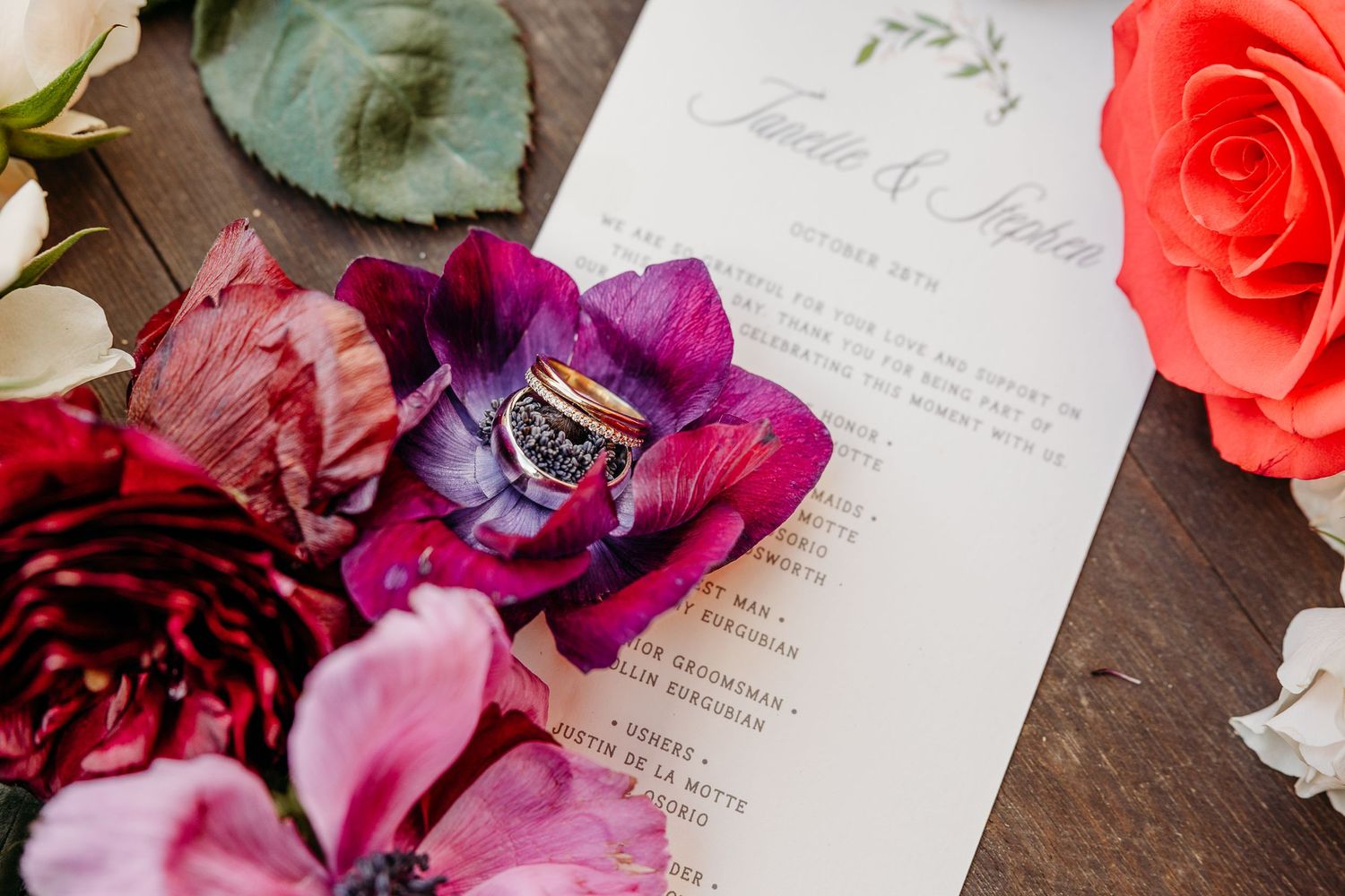 Beautiful coral roses and purple orchids arranged with handwritten letters and vintage papers on a rustic wooden surface.