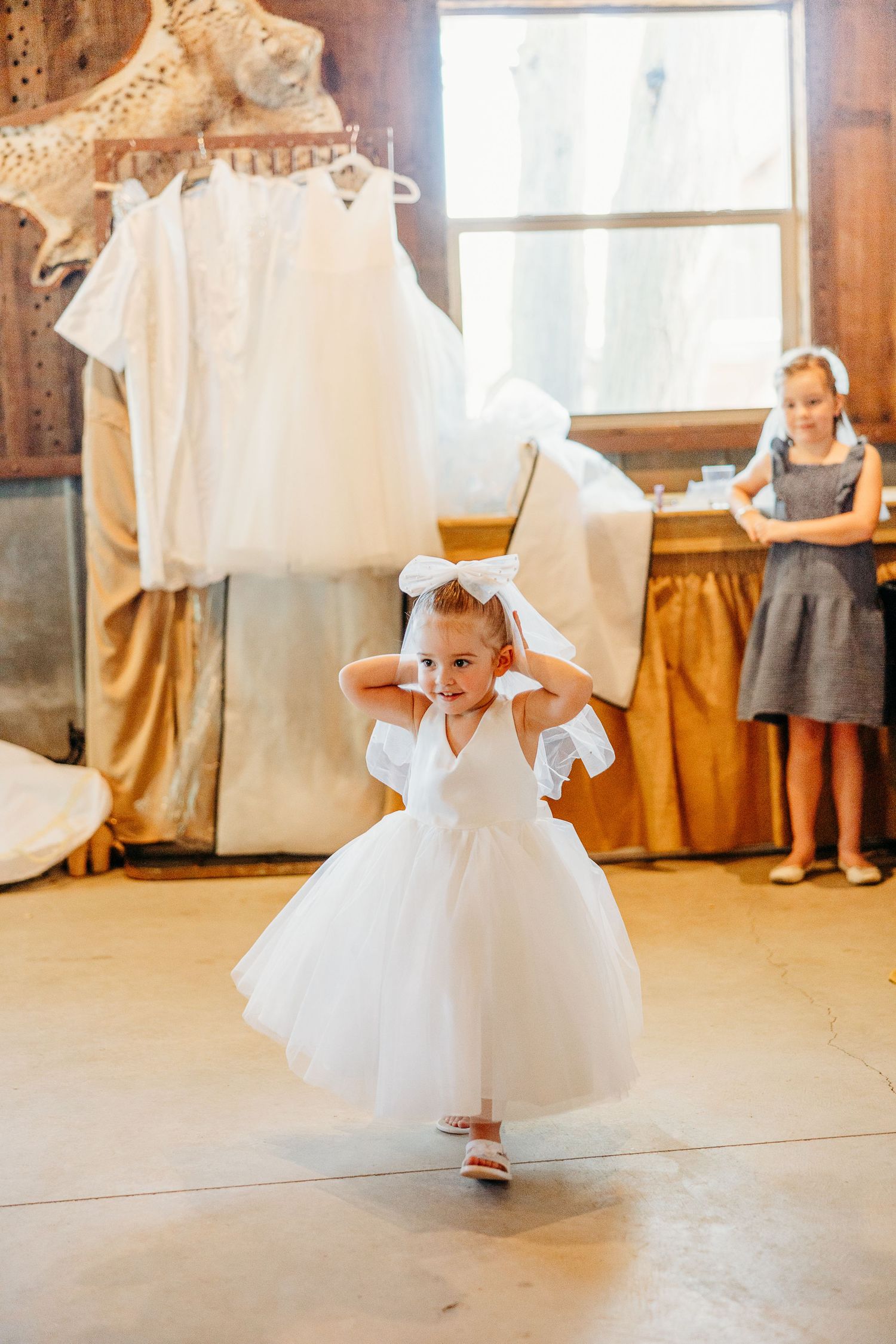 Flowing white tulle dresses twirl across a wooden floor during a wedding celebration.