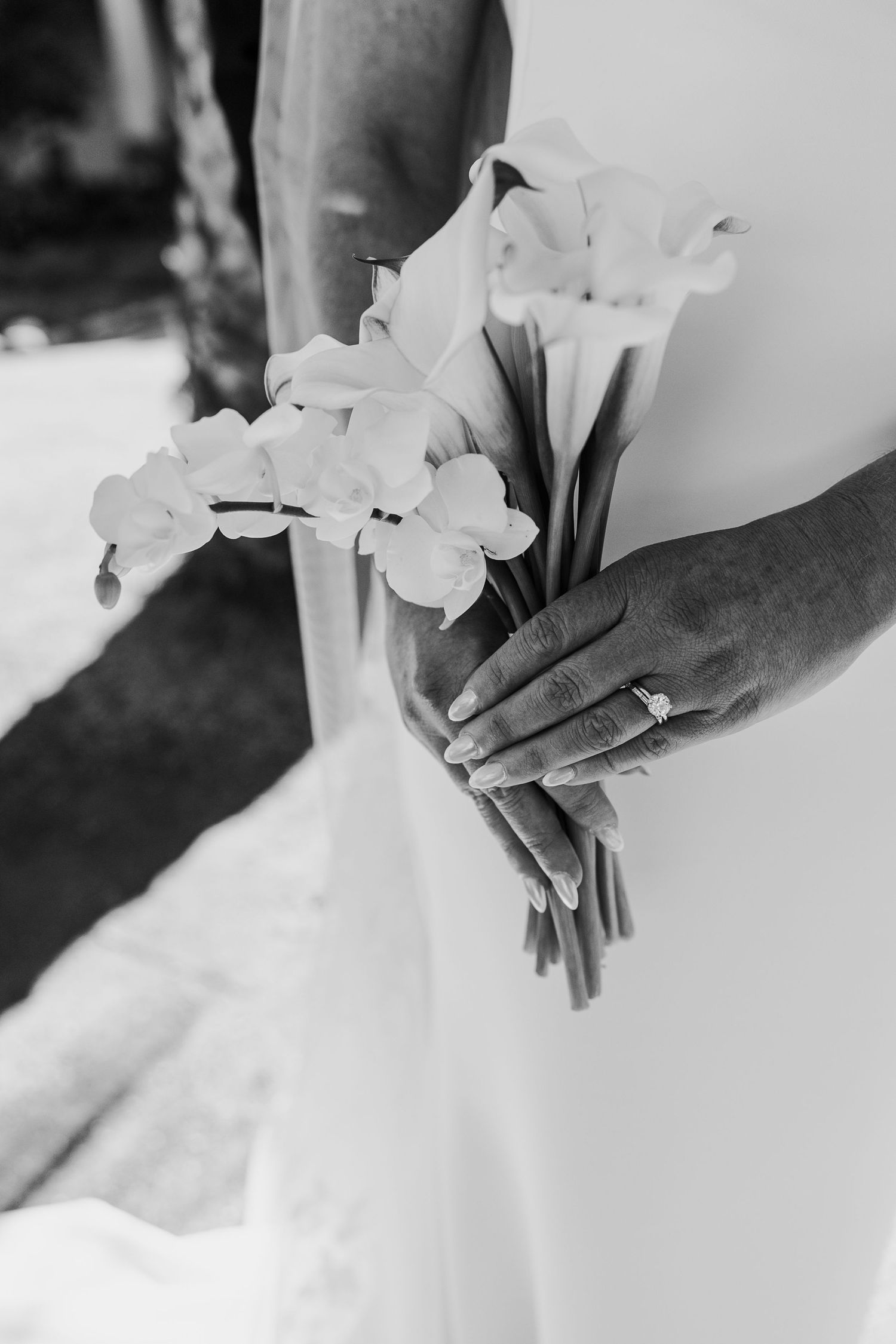Series of black and white detail shots showing delicate white flowers held against a wedding dress.