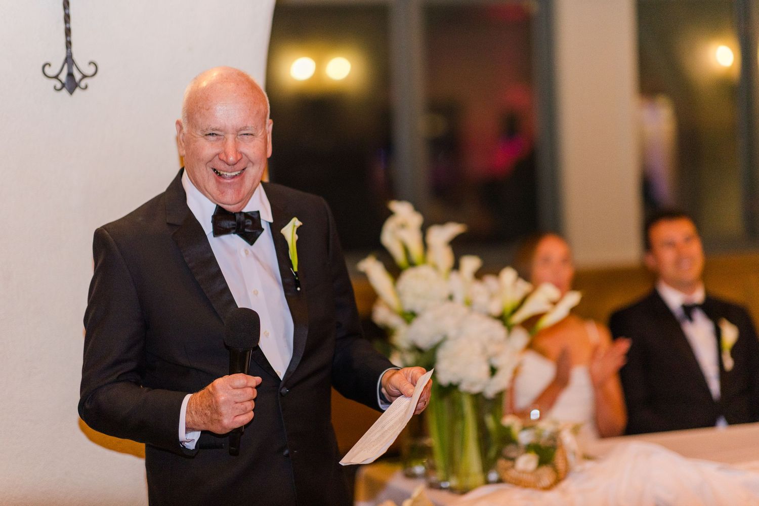 Wedding reception venue with warm lighting and elegant table settings.