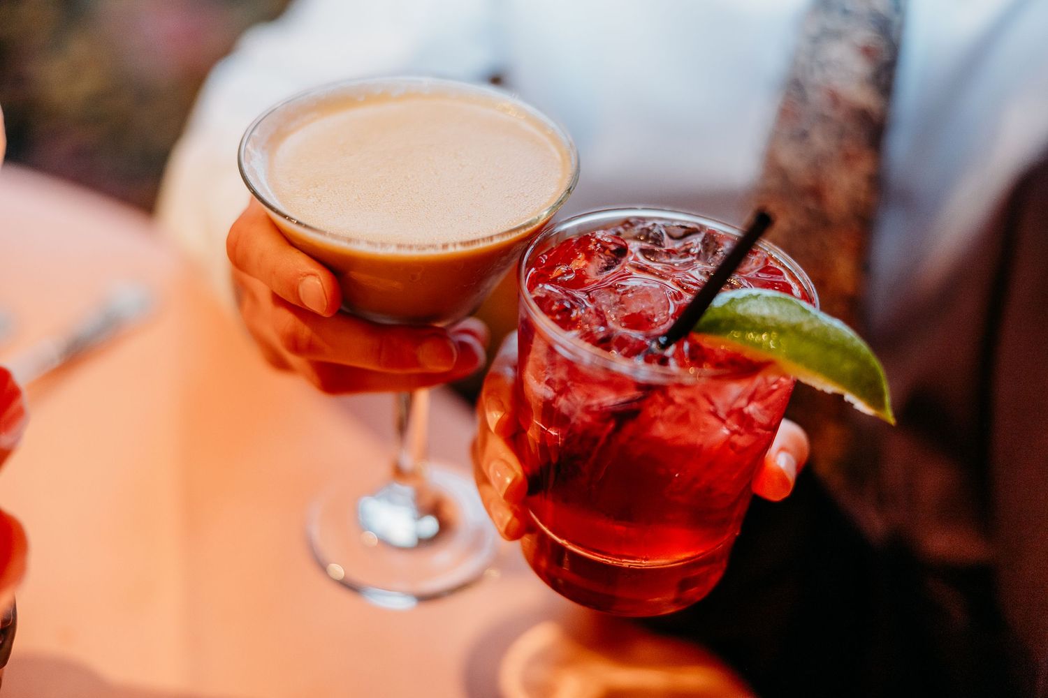 Colorful cocktails and drinks lined up on an illuminated bar surface.