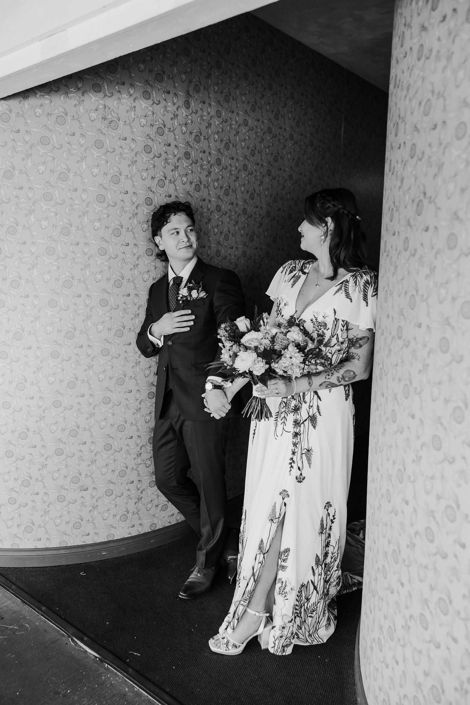 Black and white artistic wedding photos showing intimate moments in a hallway with floral bouquets.