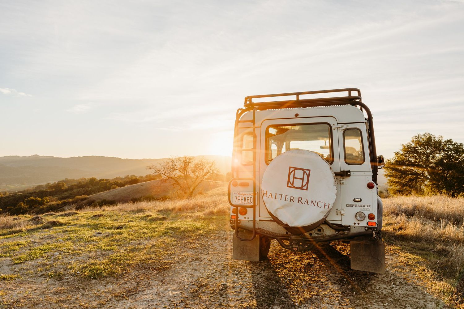 Vintage truck parked in rolling hills during golden hour with Belle Branch logo visible.