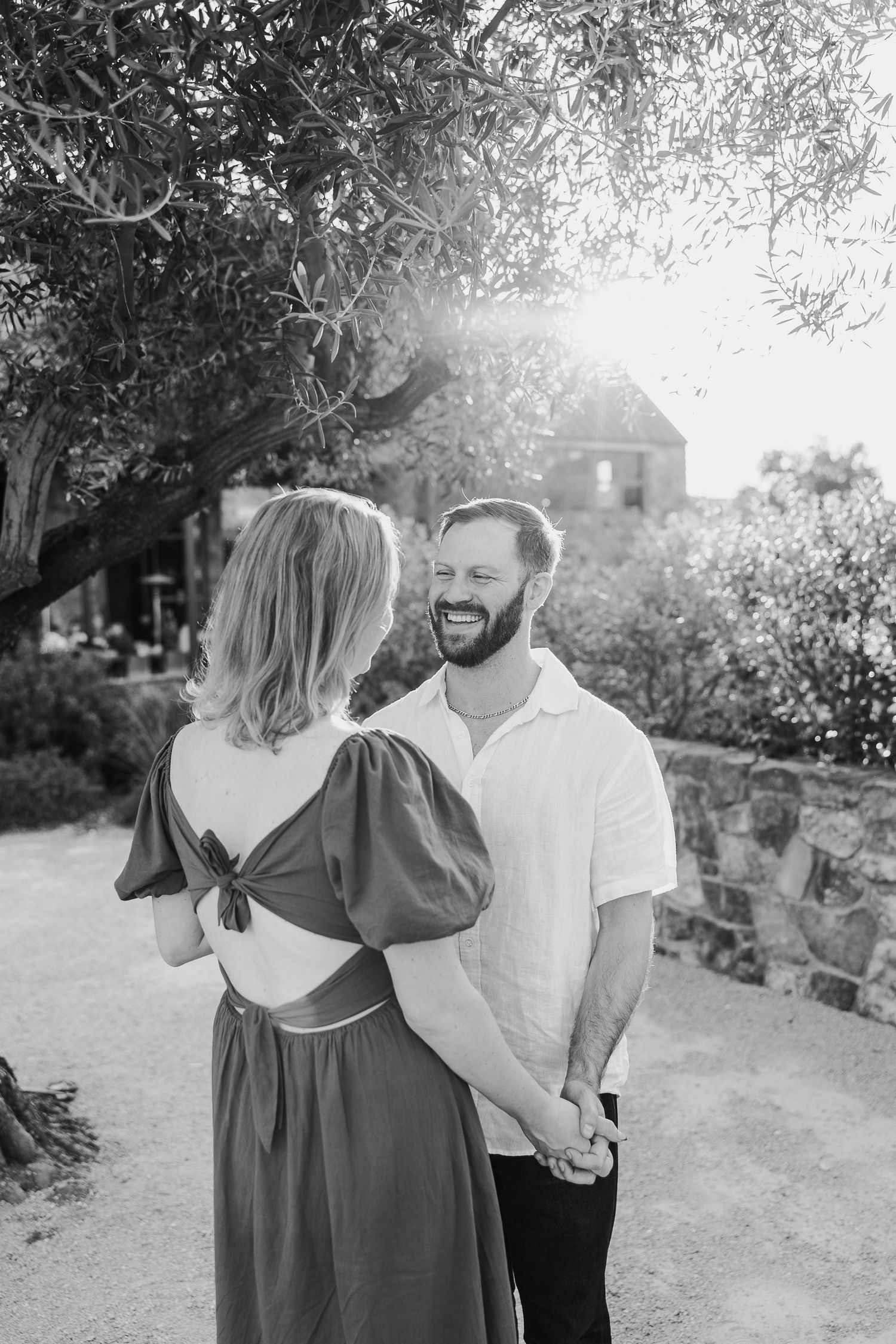 A couple shares intimate moments on a garden path during a black and white photoshoot.