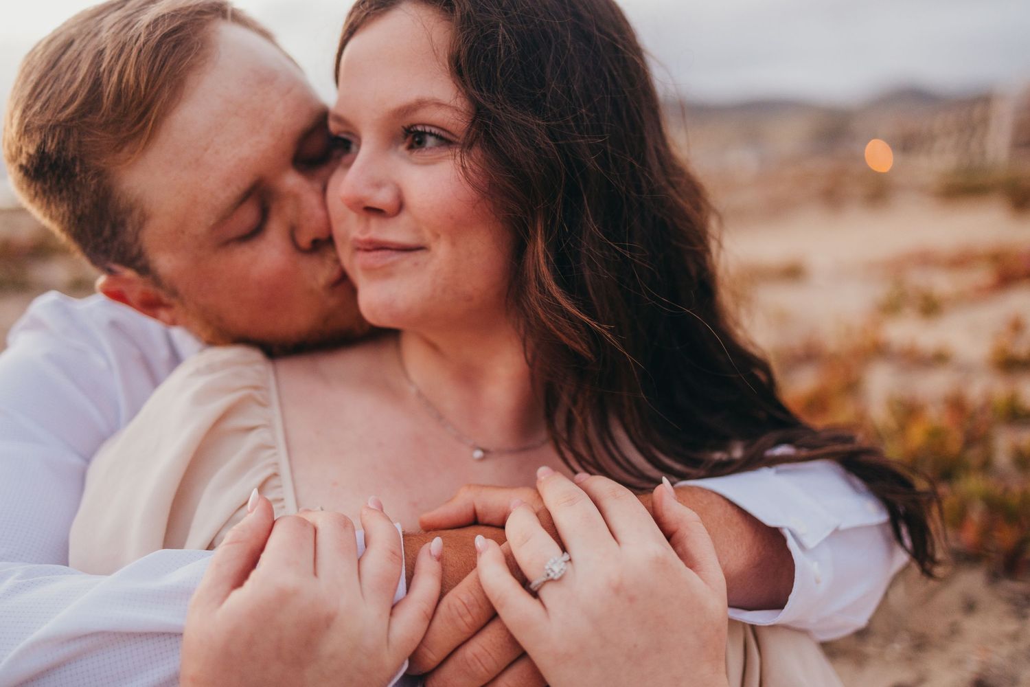 Intimate moment captured between couple against desert backdrop at sunset.