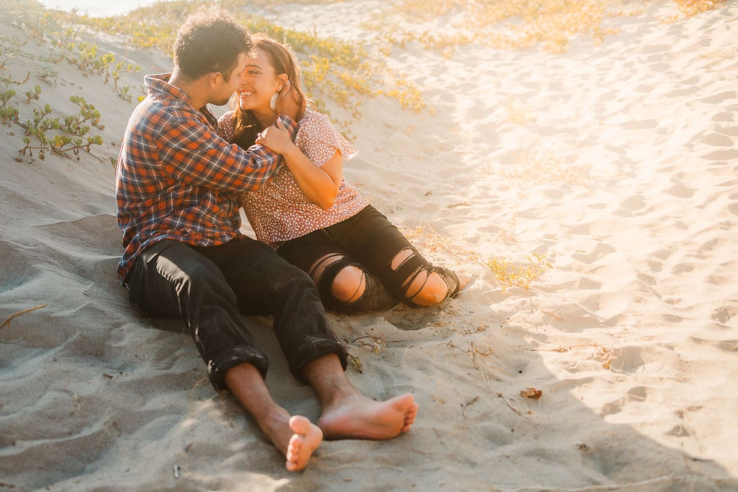 Couple sharing intimate moment on beach at golden hour.