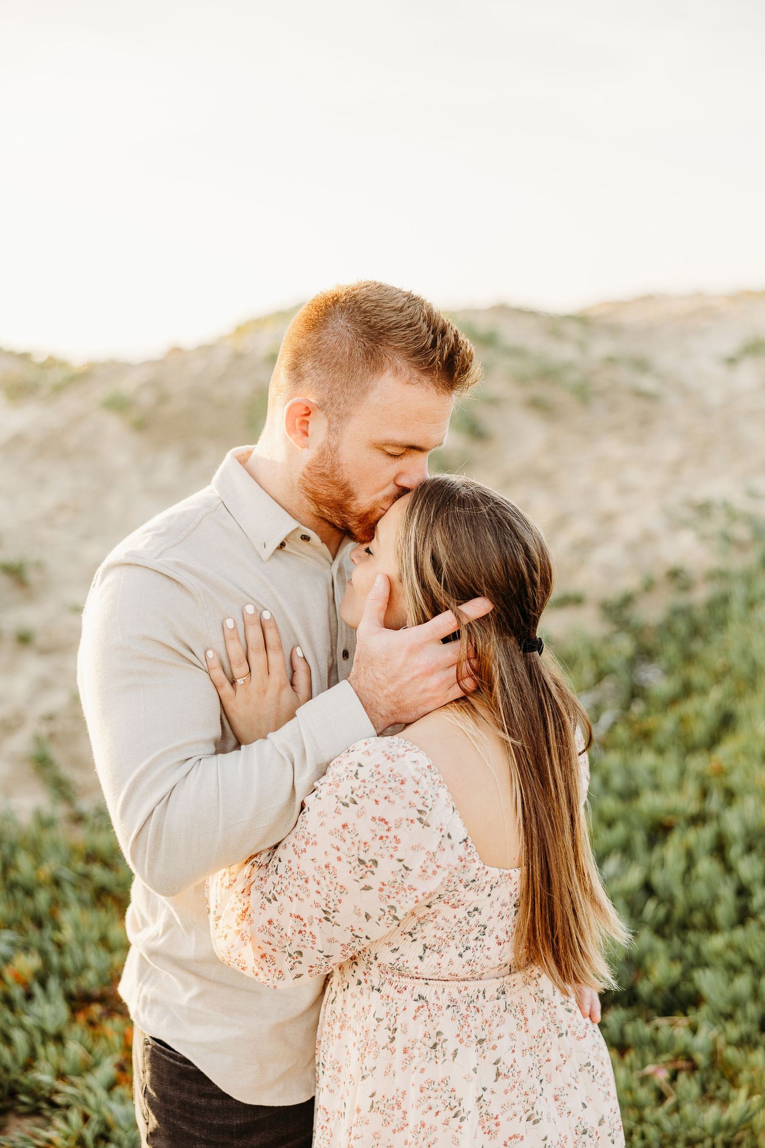 A romantic embrace captured in warm sunlight against a natural backdrop.