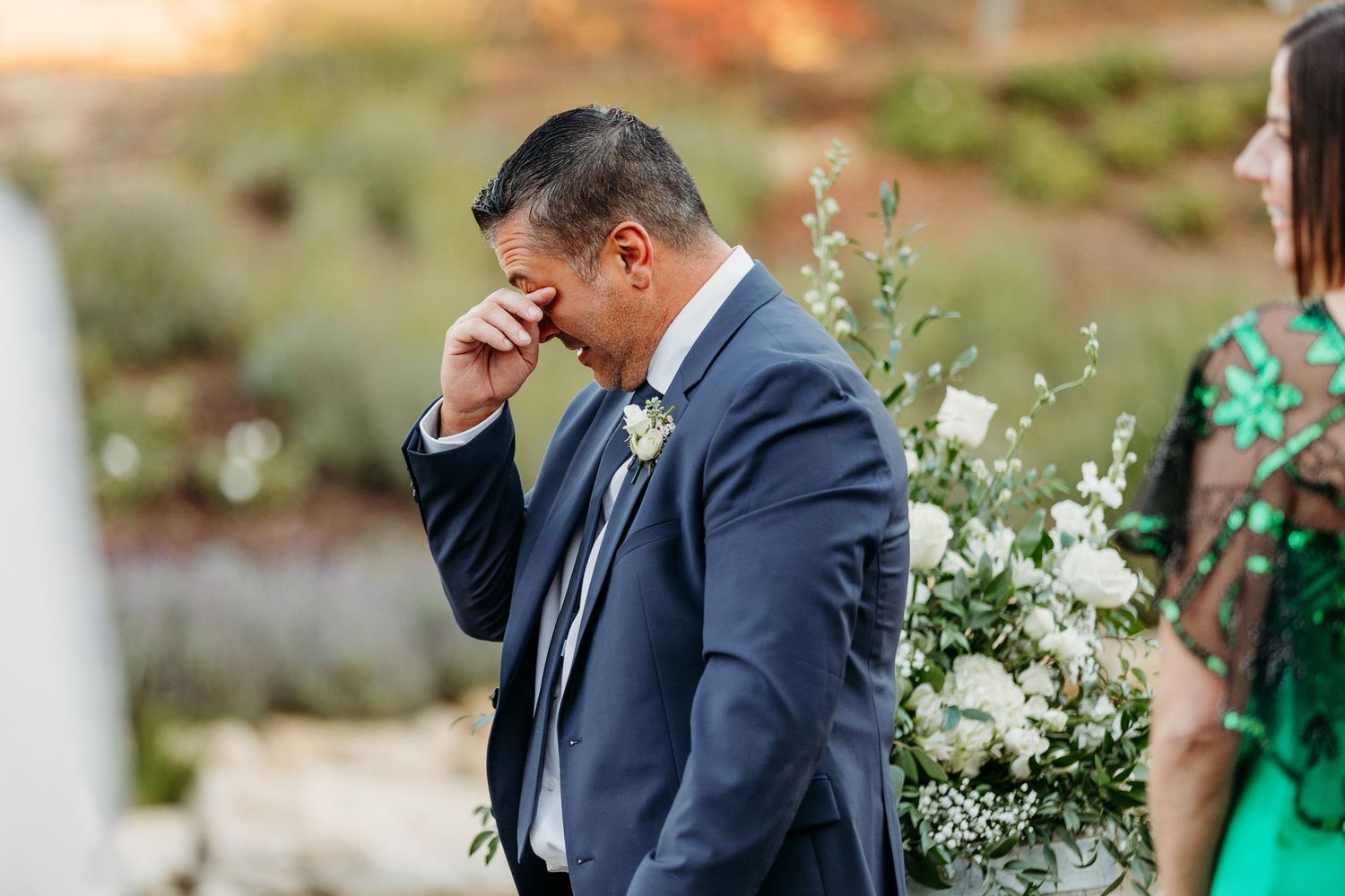 Wedding party members share emotional moments during an outdoor ceremony.