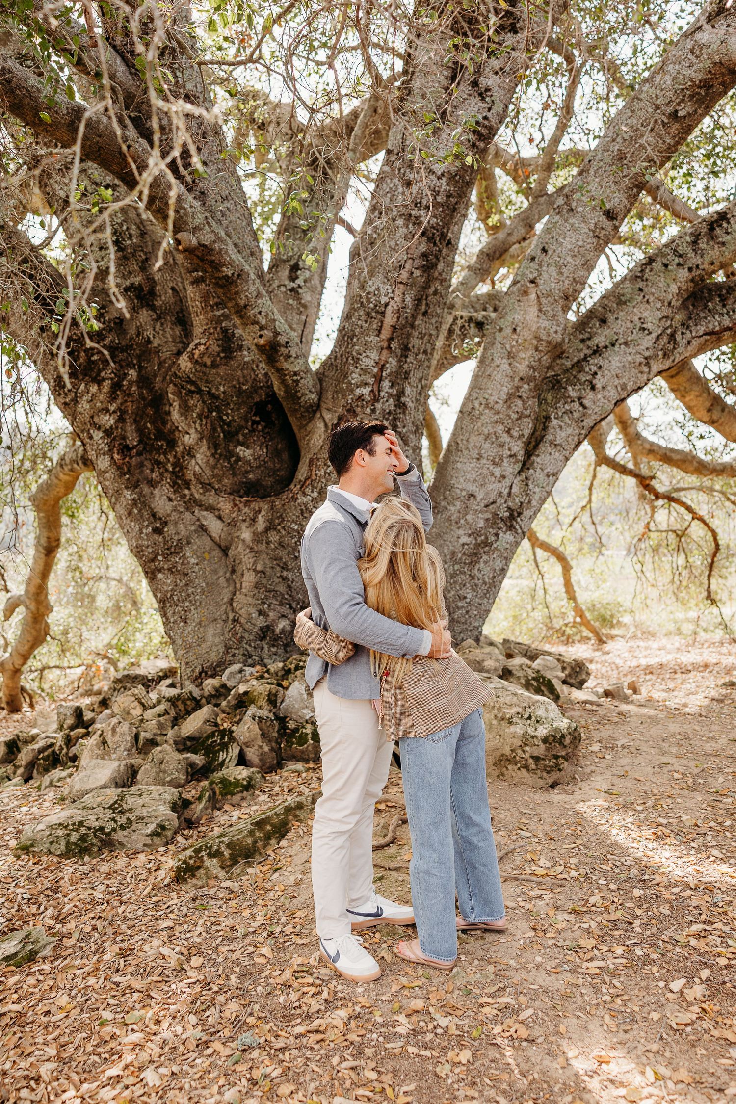 A couple shares an intimate moment under ancient oak trees during a surprise proposal.