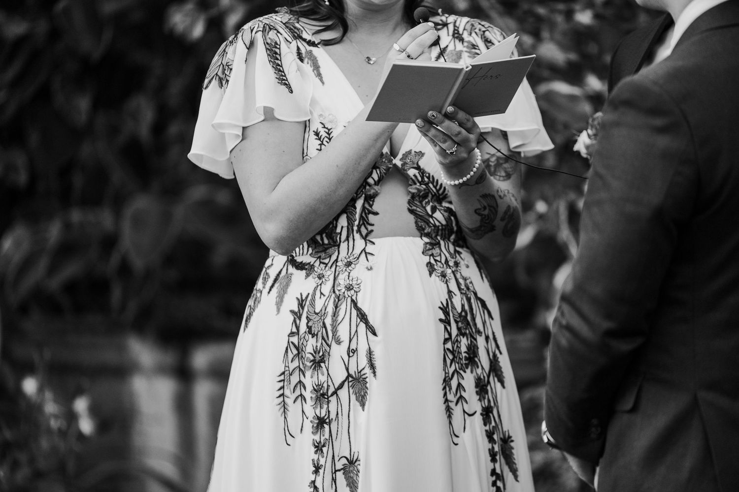Black and white wedding ceremony photo with floral dress details.