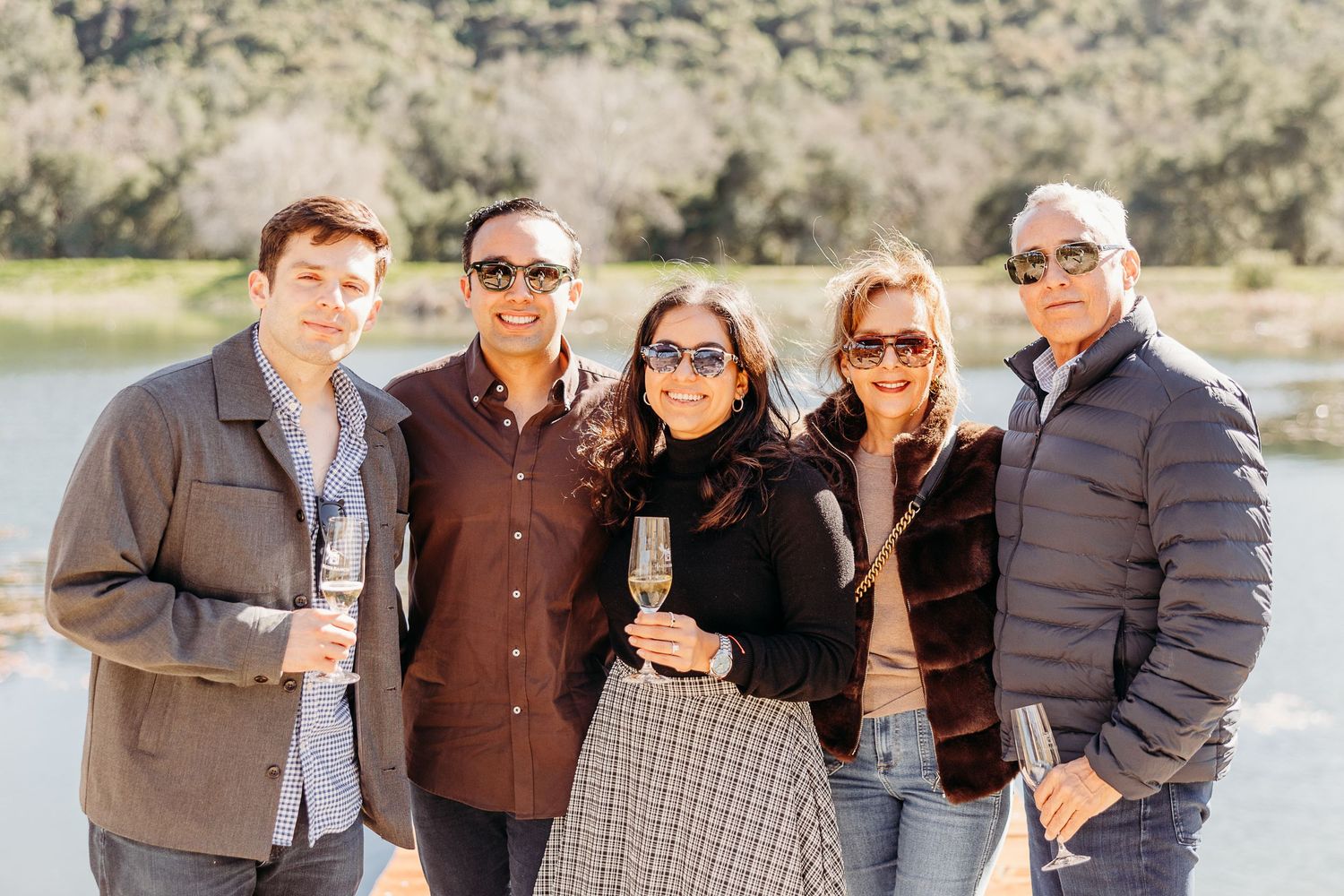 A group of people wearing casual attire pose together outdoors against a natural desert landscape background.