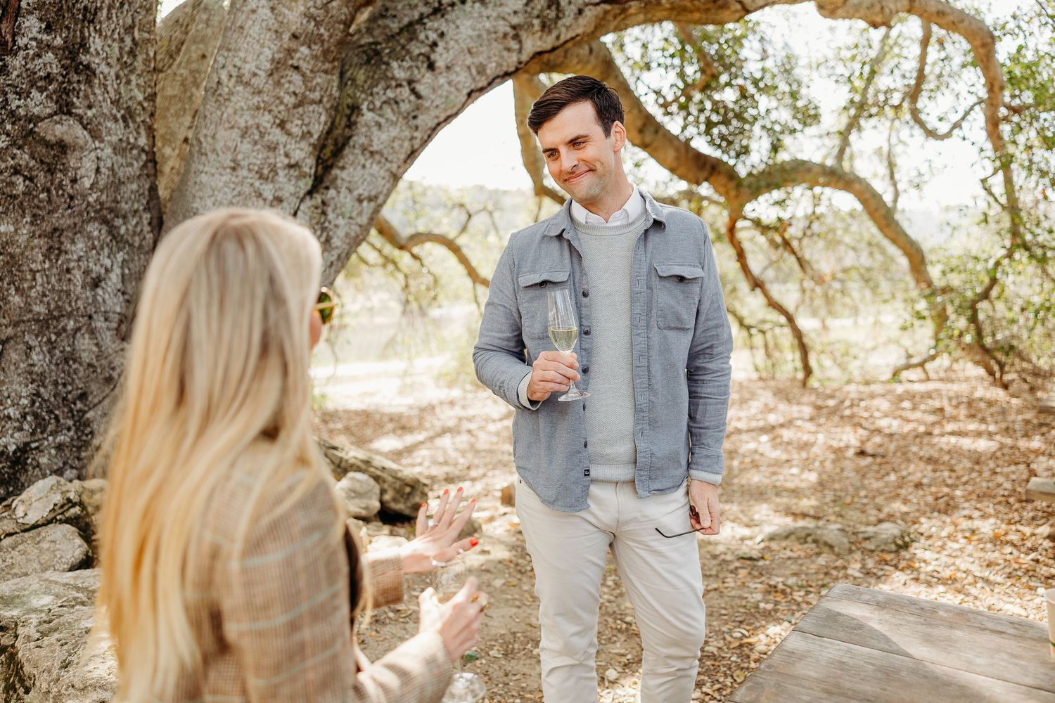 Couple sharing intimate moment beneath ancient oak tree branches.