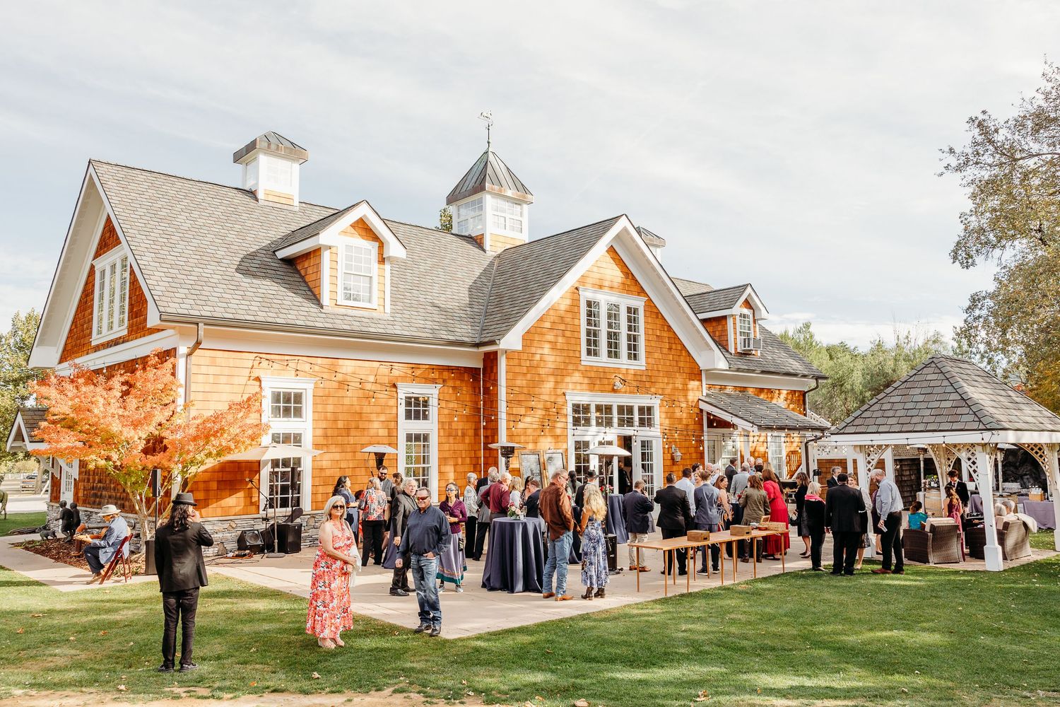 Large brick wedding venue with guests gathering outside on the lawn.