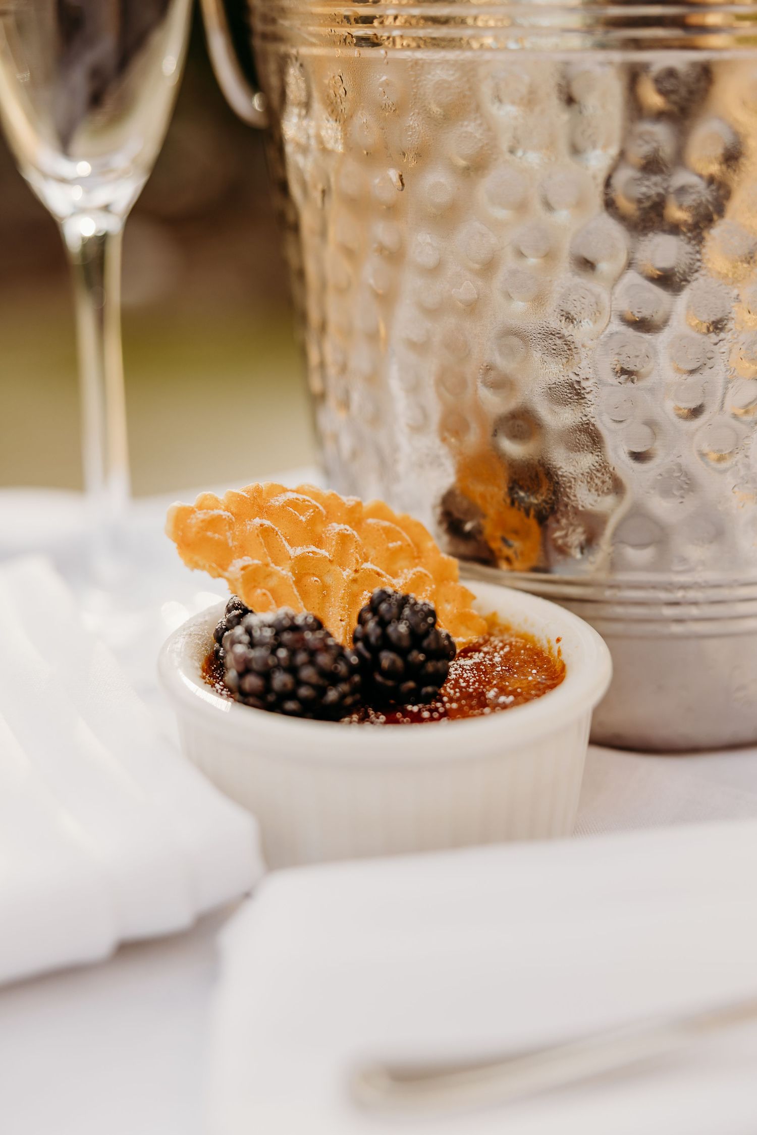 A dessert dish with fresh berries and citrus garnish served alongside a textured glass vessel.