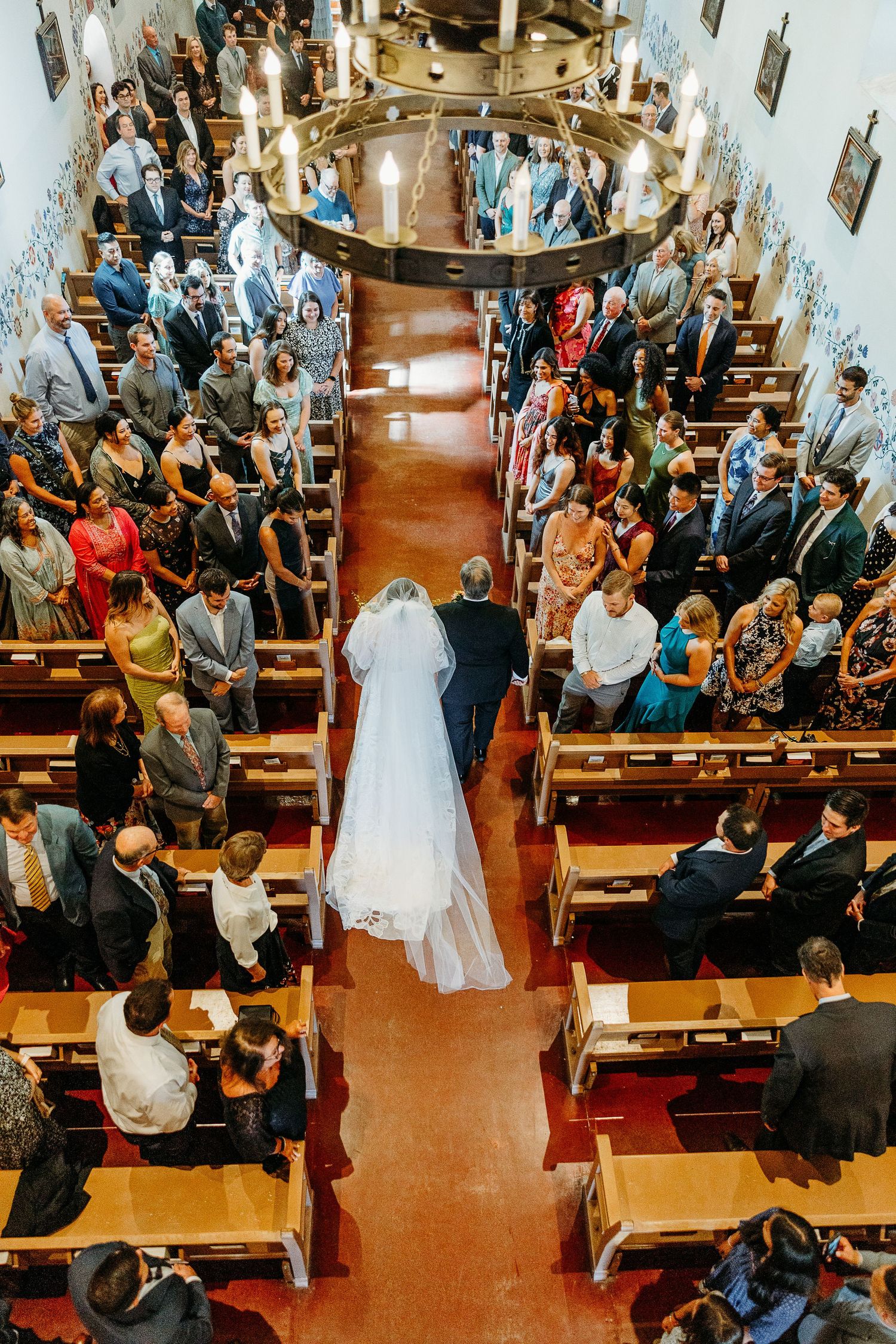 Aerial view of traditional church wedding ceremony in SLO Mission with guests seated in wooden pews.
