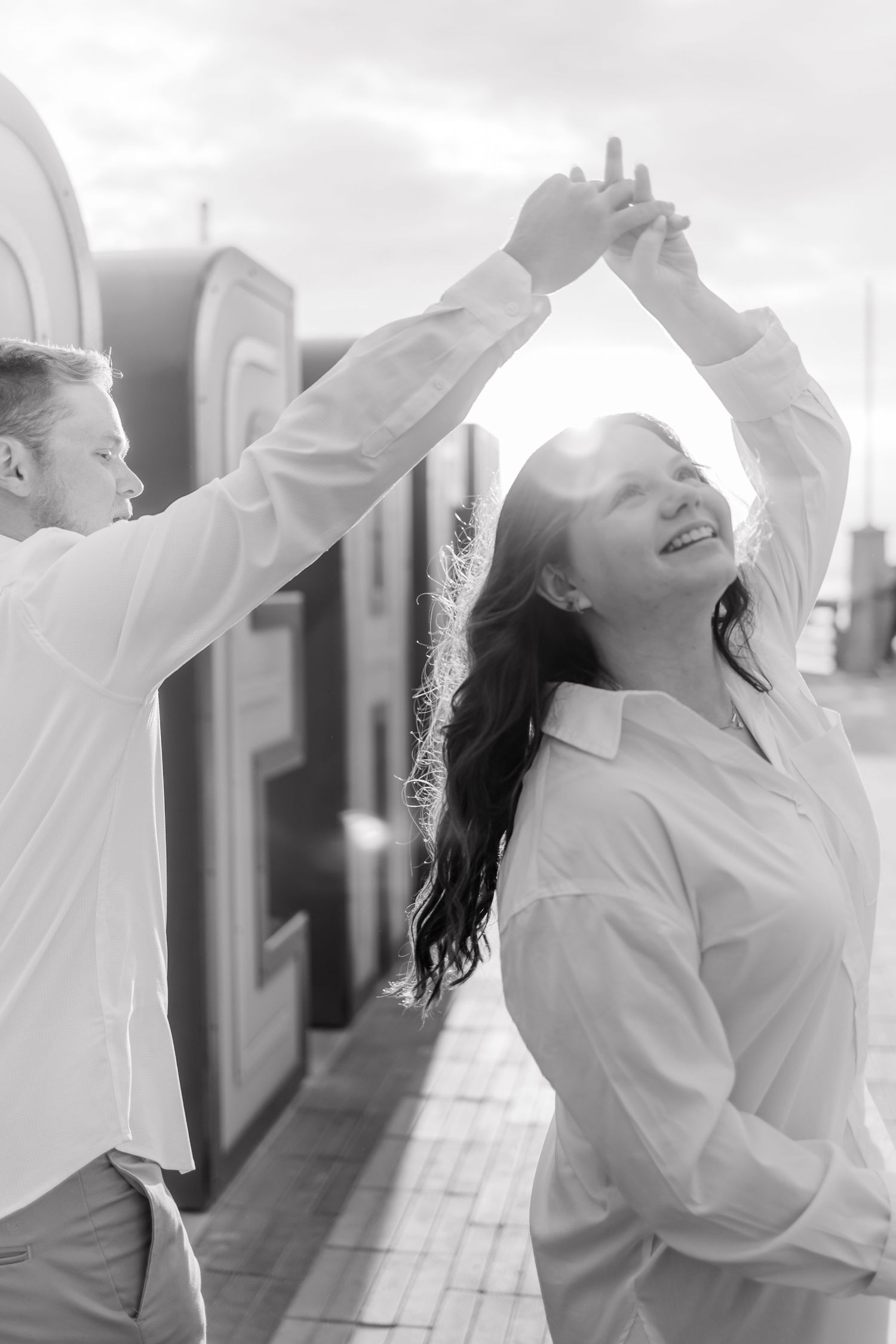 Dancing couple in white shirts spinning and laughing together by large letters in black and white.