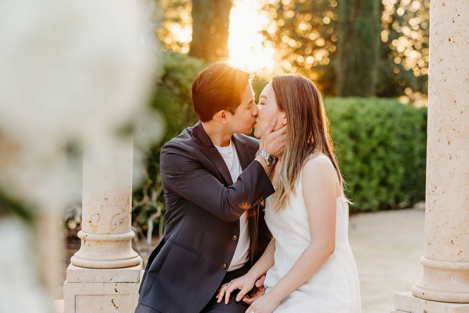 Couple sharing intimate moments in a garden setting during golden hour.