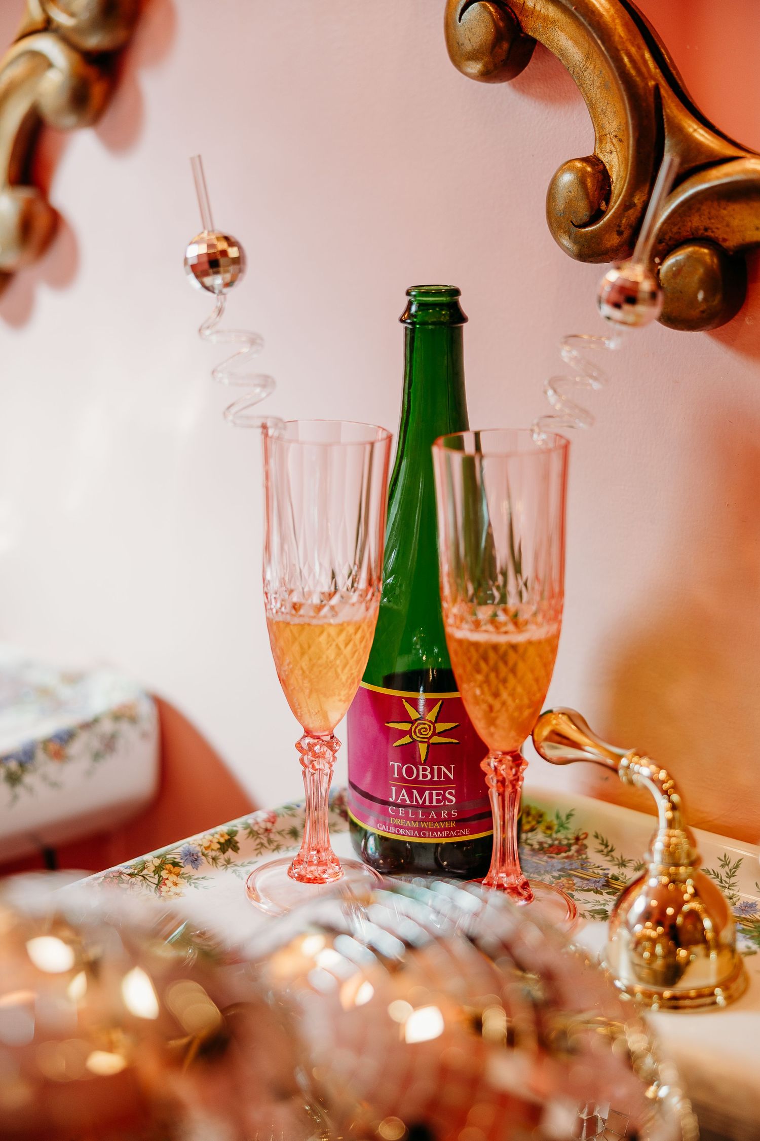 Champagne glasses and green bottles arranged with gold decor elements in warm lighting.