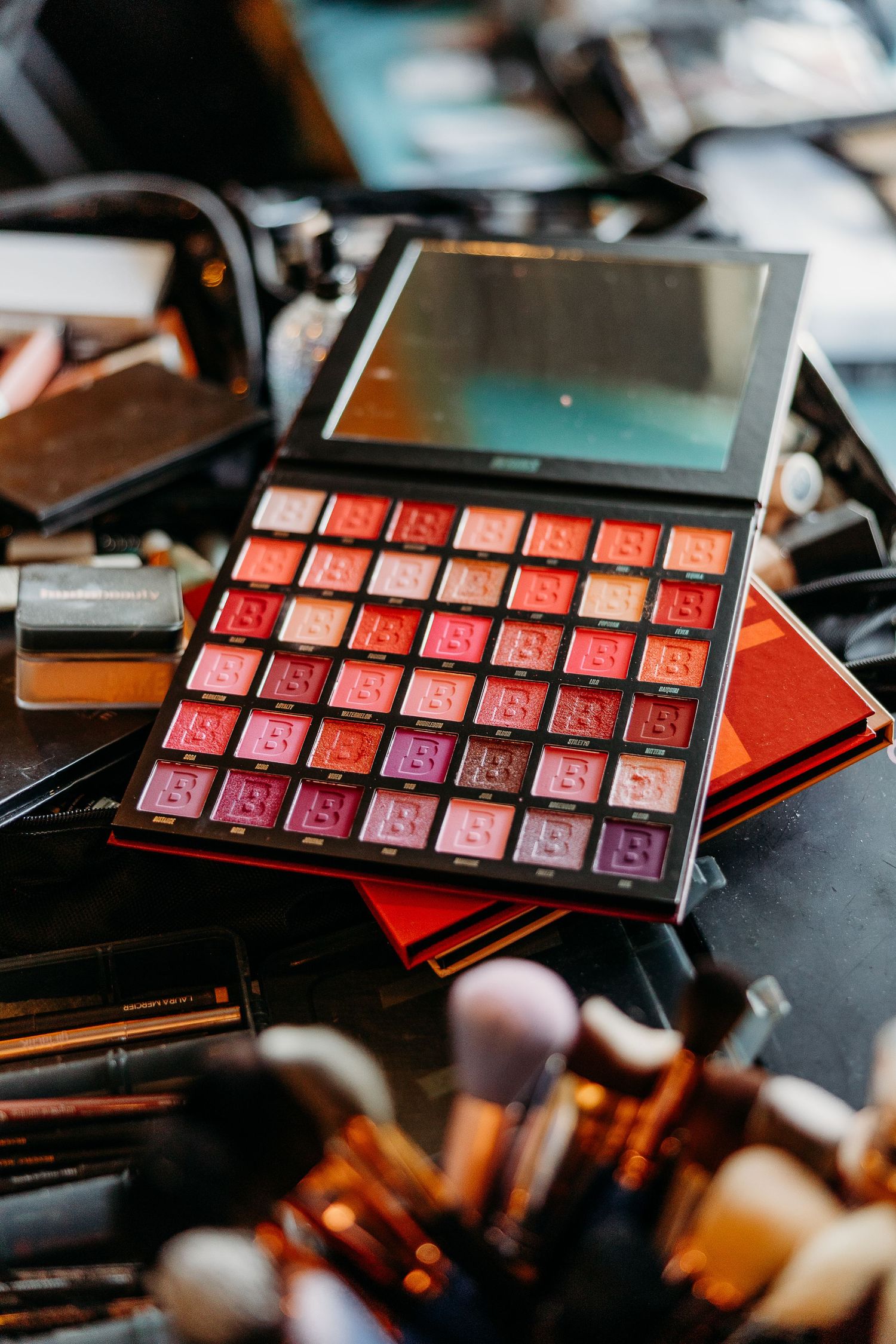 Closeup sequence of pink and red eyeshadow makeup palettes on dark surface.