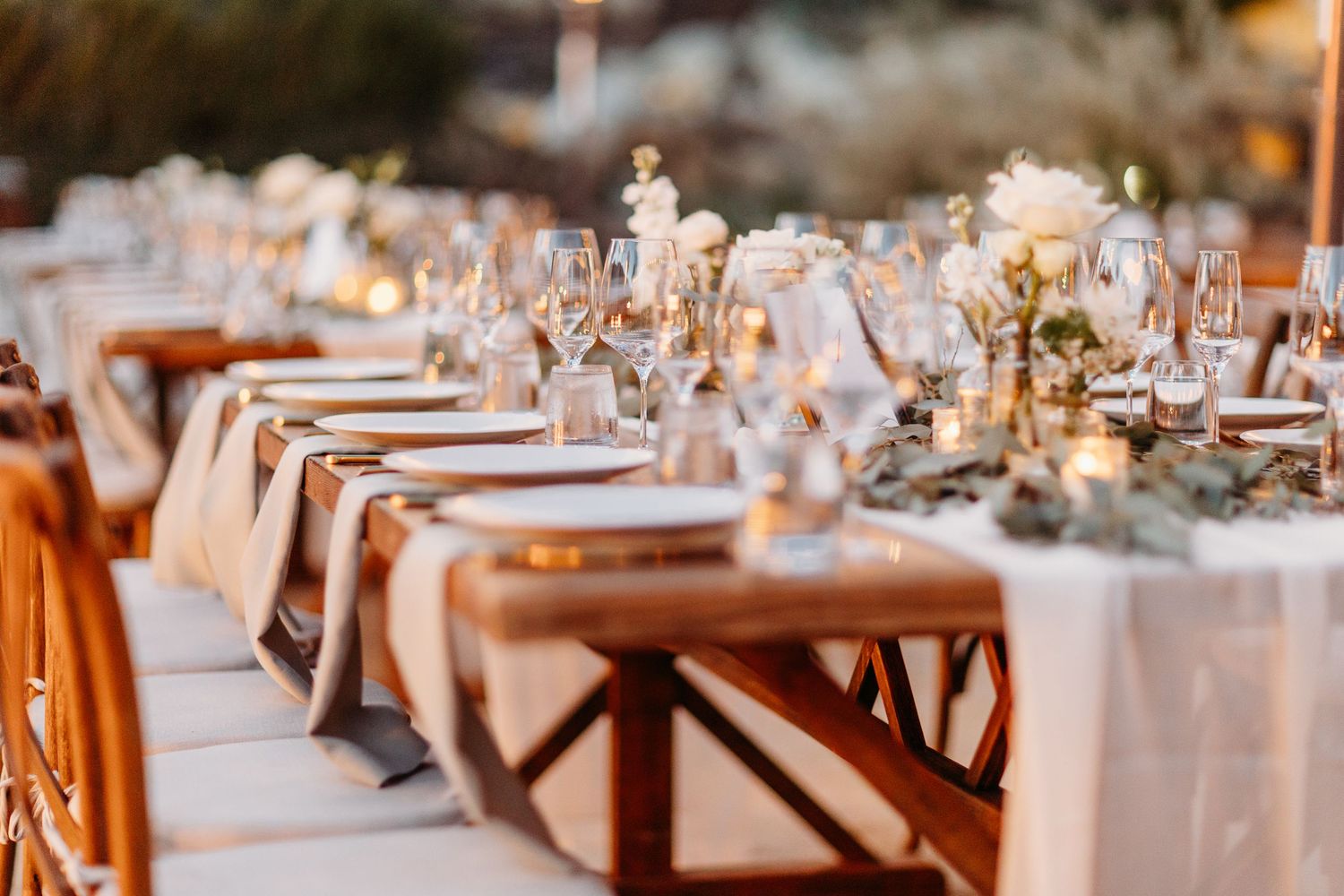 A beautifully decorated wedding reception table with white linens and warm lighting.
