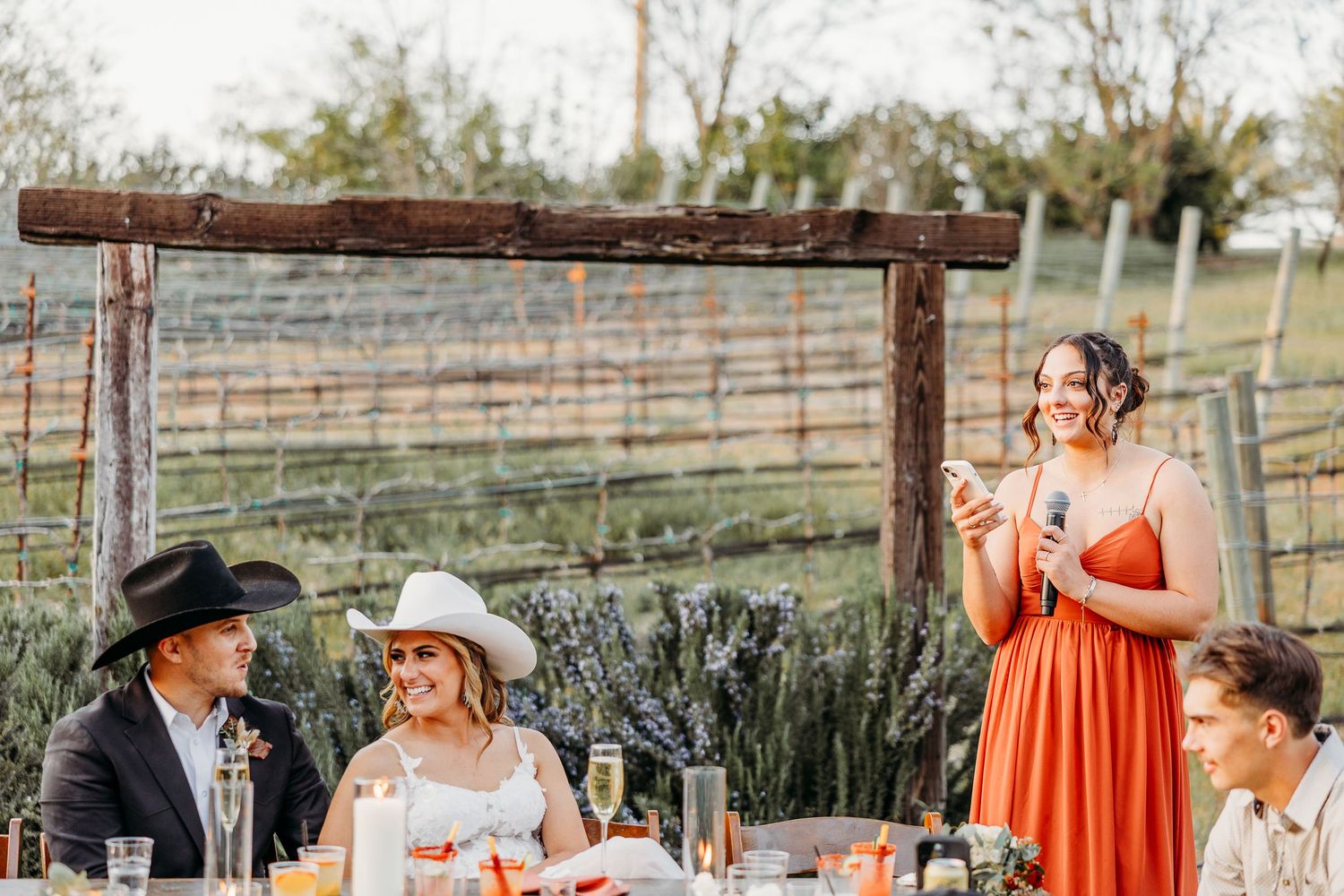 Wedding guests enjoying an outdoor reception with rustic decor and country-western theme.