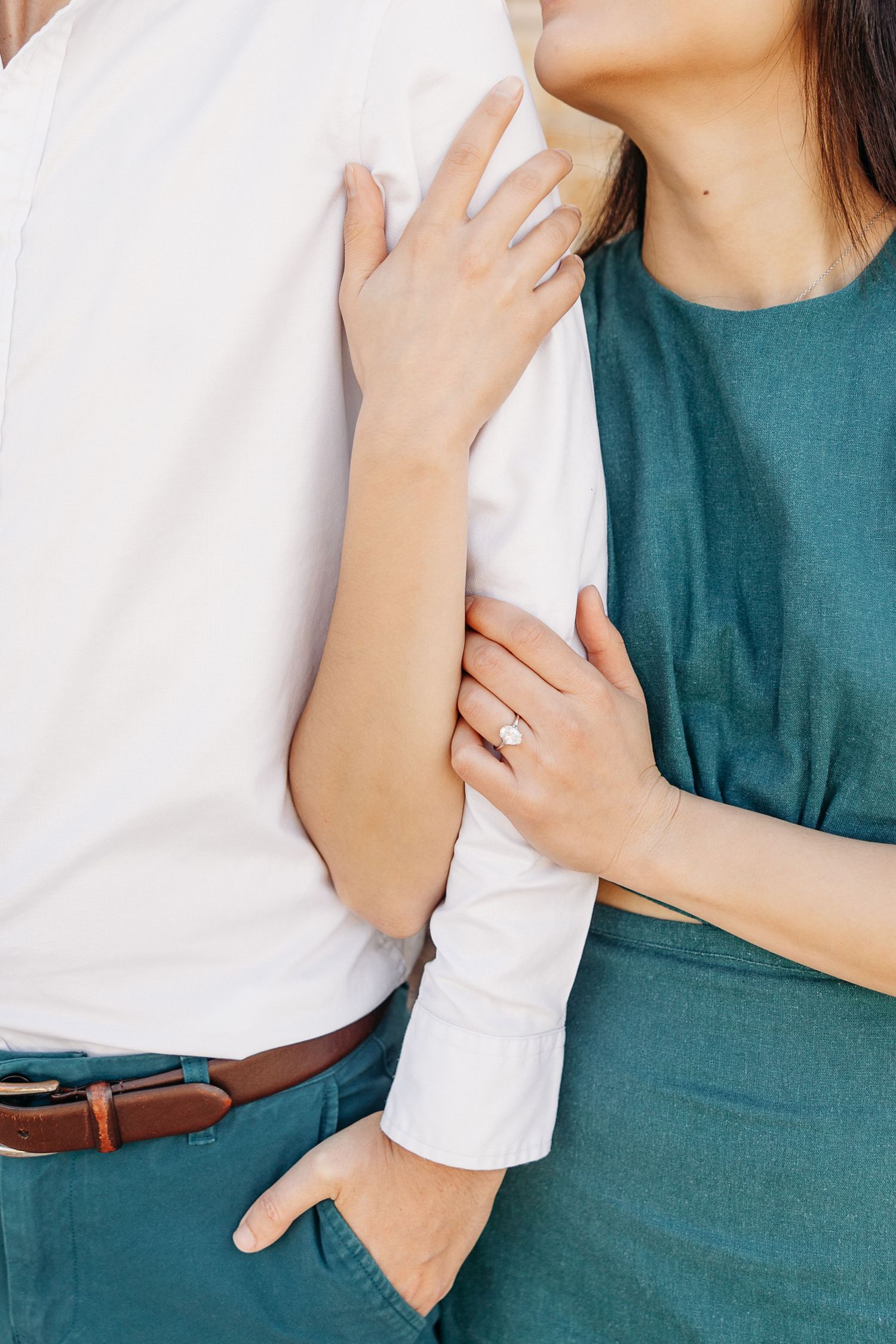 A couple wearing teal and white embraces in a romantic series of cropped photos showing their torsos and hands.