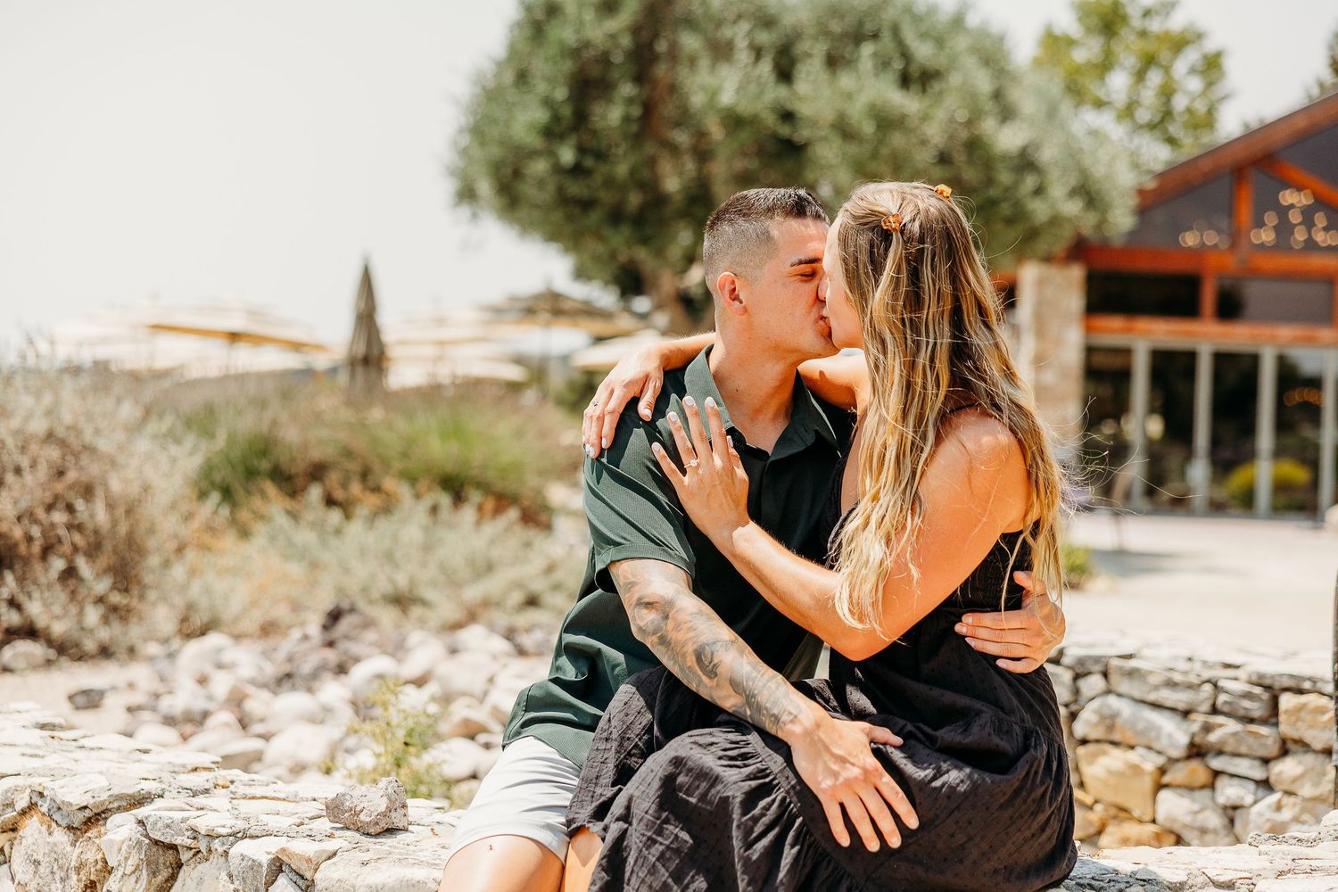 A couple dances and embraces in front of a modern building with mountains visible in the background.